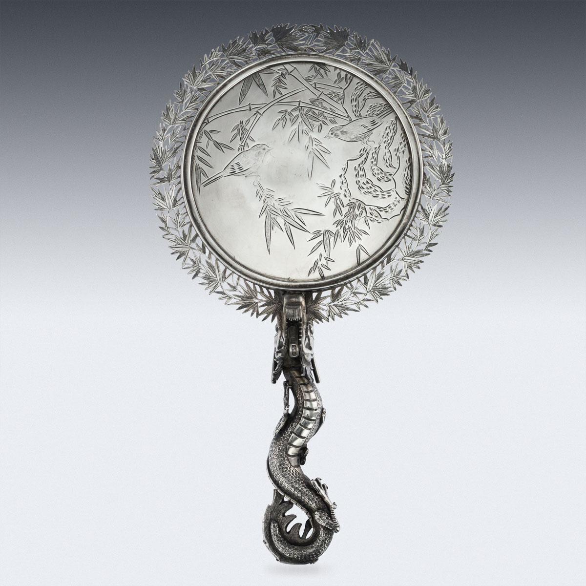 Antique 19th century rare Chinese Export solid silver hand mirror, of round form, very large size and heavy gauge, the handle formed as entwined dragon biting into the mirror, the double sided mirror surrounded by an outstanding openwork frame,