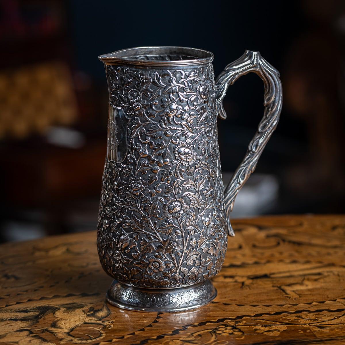 Antiguo aguamanil chino de plata maciza de exportación de mediados del siglo XIX, con una intrincada decoración de hojas y flora sobre fondo mate. El mango, con forma de rama de árbol, está fijado a un lado. En el lado del pitorro hay unas iniciales
