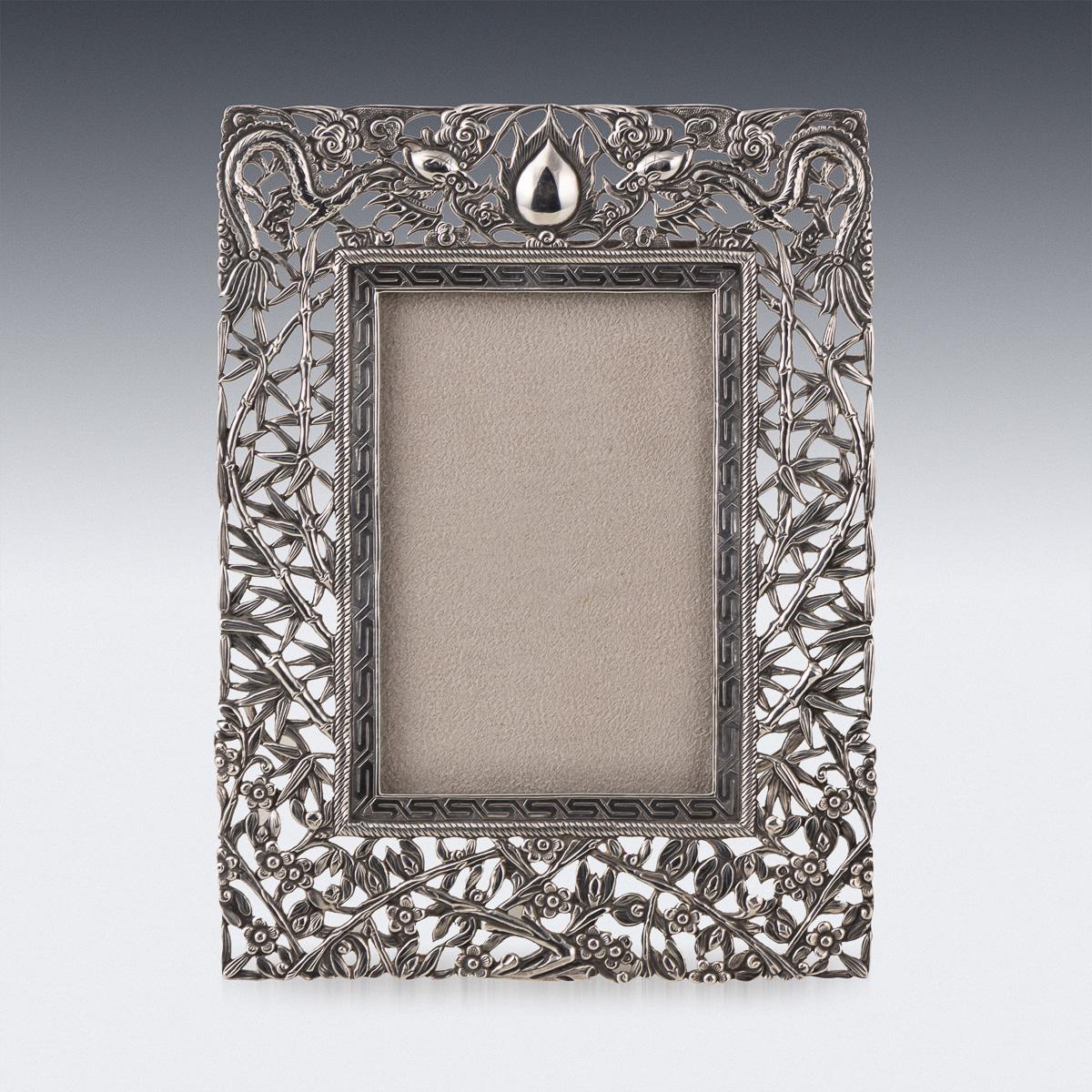 Antique 19th Century Chinese export solid silver picture frame, of rectangular form, with chased decoration and pierced in high relief, depicting various illustrated flowers, bamboo and two dragons. There is a geometric pattern surrounding the glass