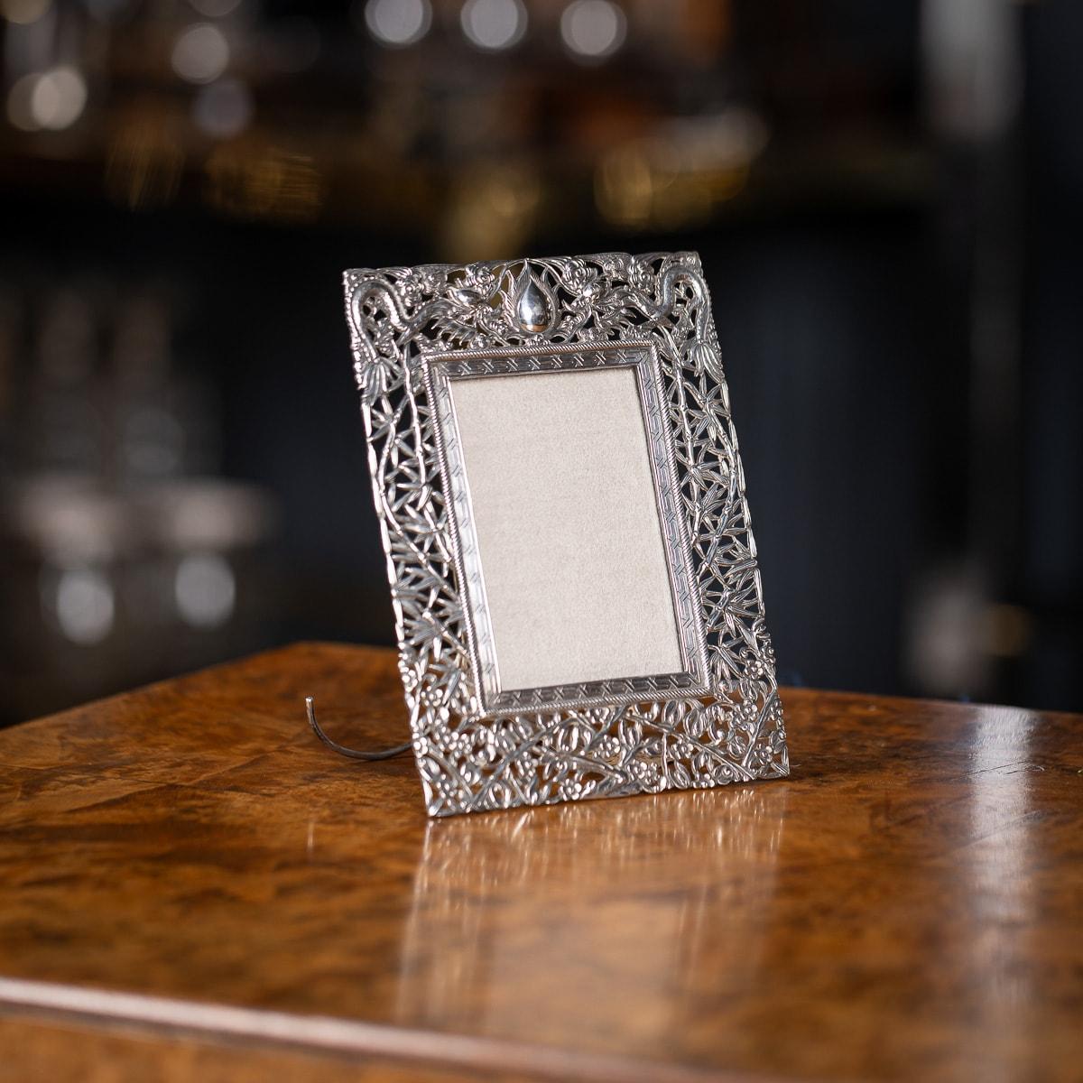 Antique 19th Century Chinese export solid silver picture frame, of rectangular form, with chased decoration and pierced in high relief, depicting various illustrated flowers, bamboo and two dragons. There is a geometric pattern surrounding the glass