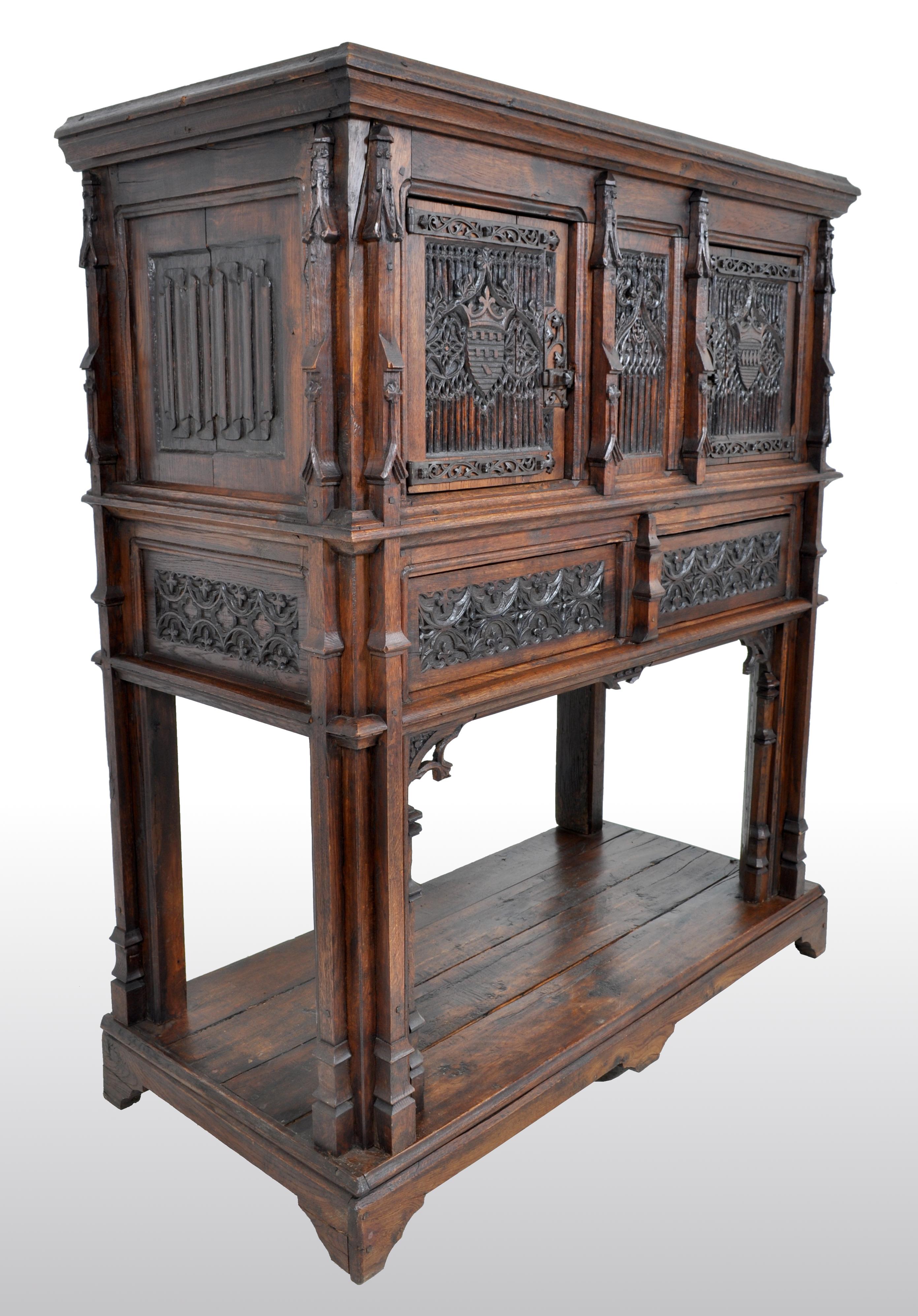 Antique French Gothic oak chalice court / cabinet / sideboard, circa 1860. The cabinet in two sections, having Gothic pinnacles on the sides and front, the front having two cupboard doors and a central panel with linen-fold carving, quatrefoils, and