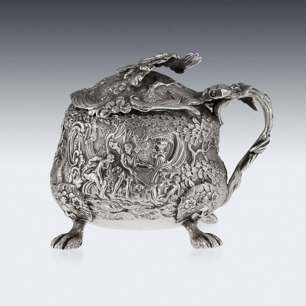 Antique early-19th century Georgian solid silver mustard pot, of squat circular form on four lion paw shaped feet, exceptionallydecorative, all-over chased in relief with hunting and courting scenes amid trees, the handle realistically formed as a