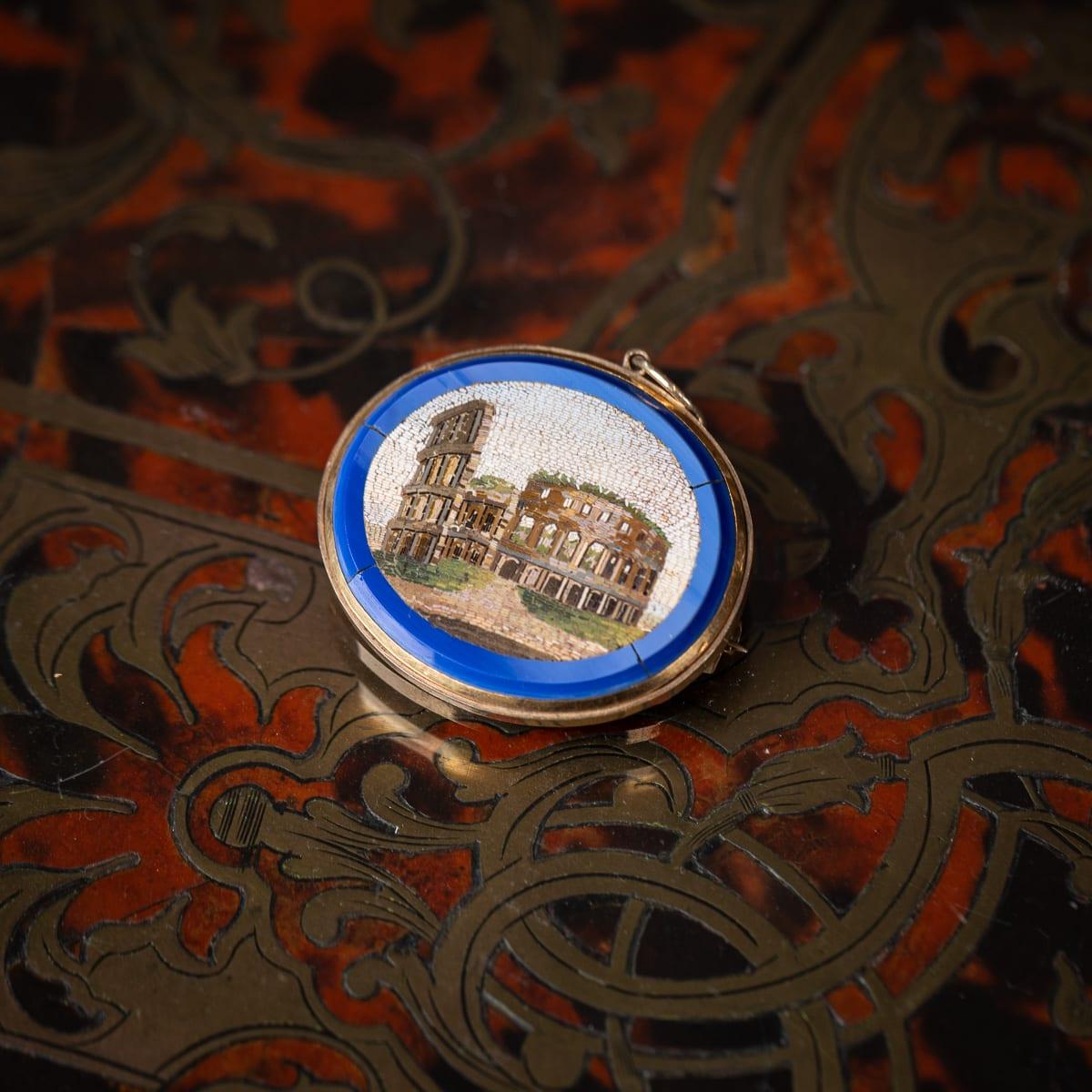 Broche / pendentif en micro-mosaïque du 19e siècle italien, encadré d'or, pour le Grand Tour. L'œuvre d'art centrale présente une micro-mosaïque représentant le Colisée romain. Merveilleusement réalisé avec un entourage de verre bleu puis encadré