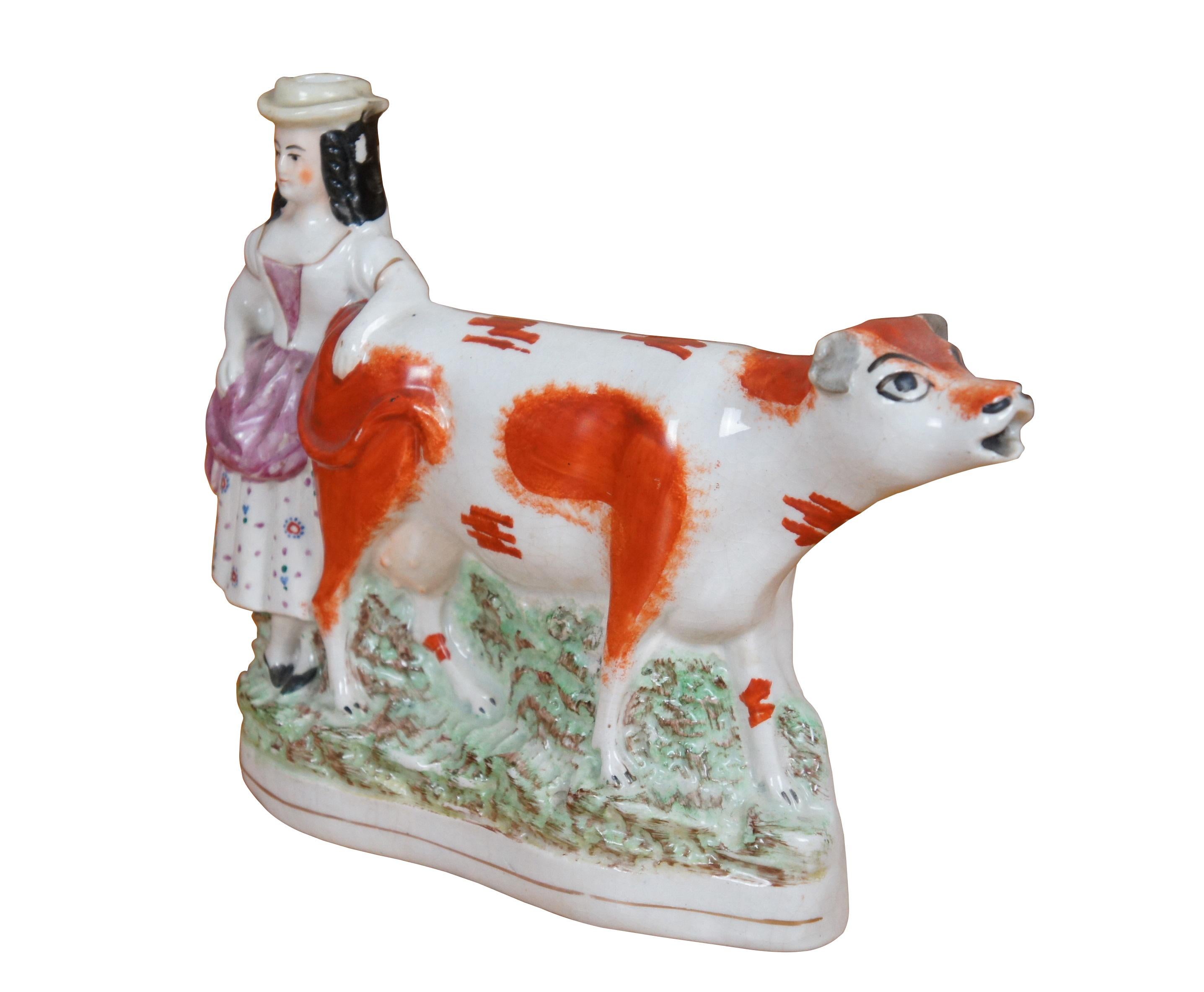 Large antique 19th century Staffordshire porcelain flatback figural spill vase / creamer in the shape of a peasant girl / milkmaid in a floral skirt, leaning on a red and white spotted cow.

Dimenisions:
9.5