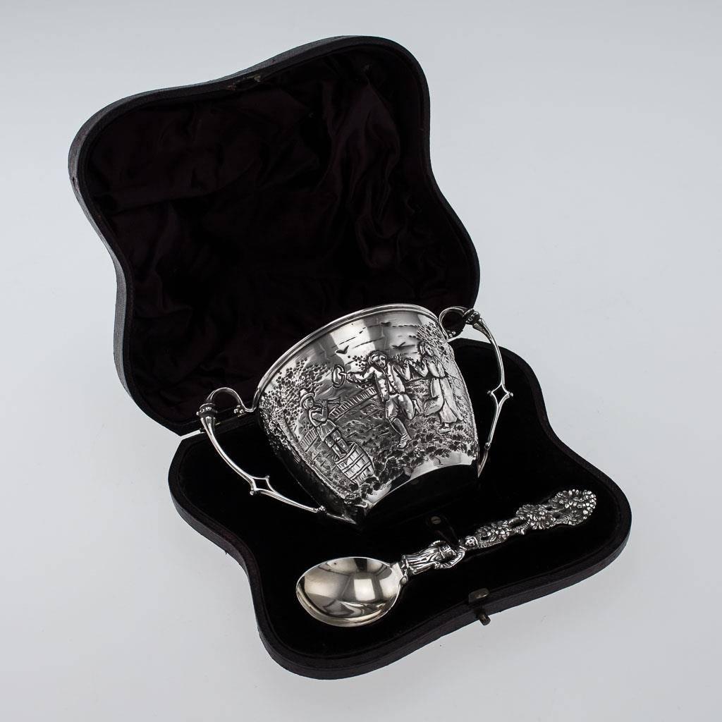 Antique 19th century Victorian solid silver christening set, comprising a two-handle cup and a spoon, in the original fitted case, both pieces are very decorative, the cup embossed in with peasants dancing in a landscape, the spoon is also