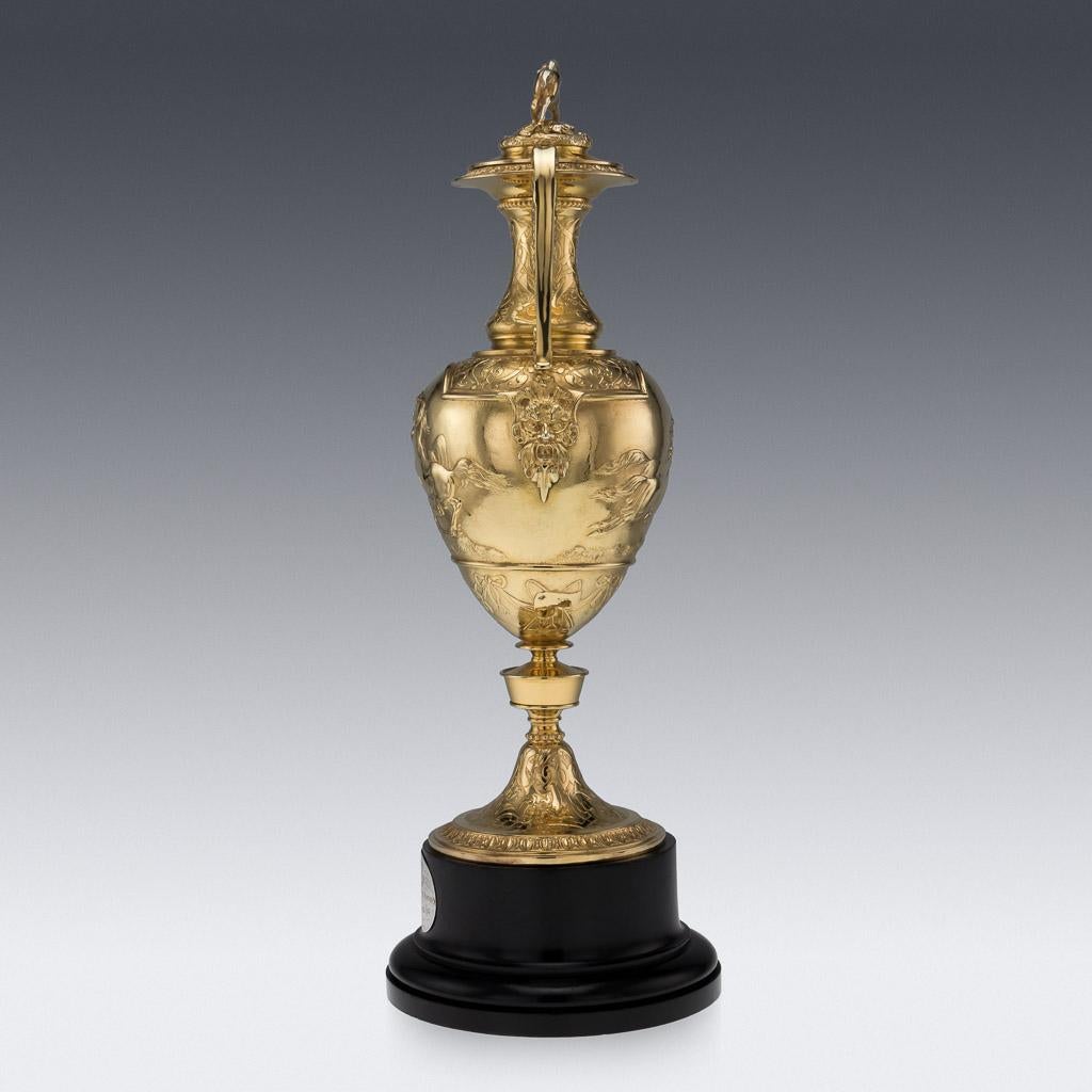 Antique 19th century Victorian solid silver trophy cup and cover, richly gilt, large, heavy and highly decorative, the baluster form body with cast handles with mask junctions, the tall neck supporting a cover surmounted by a cast finial modelled as