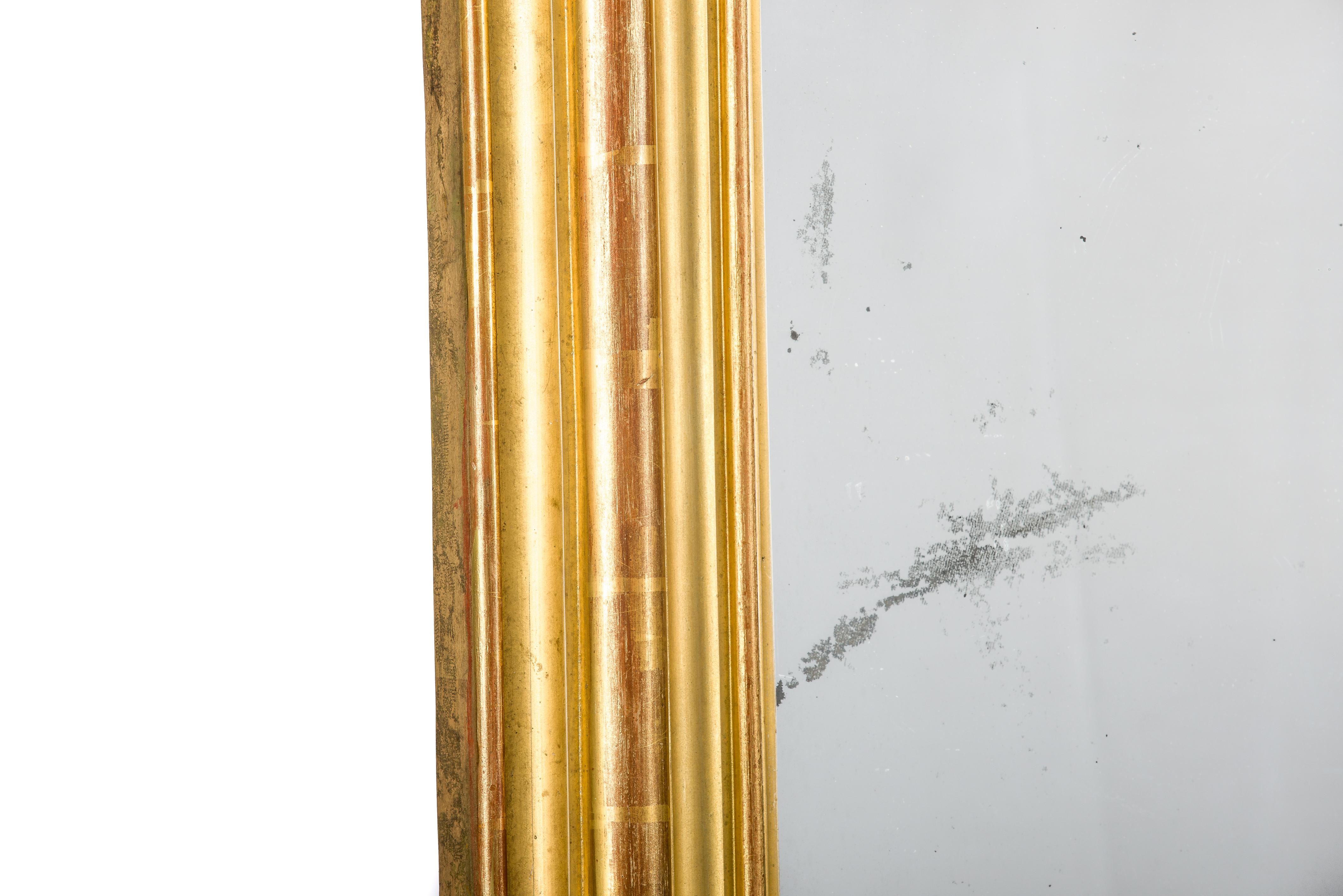 Ce monumental grand miroir doré à la feuille d'or a été fabriqué en France au milieu du XIXe siècle, vers 1830. 
Il présente les angles supérieurs arrondis typiques des miroirs de style Louis Philippe. La pièce était richement décorée de fruits, de