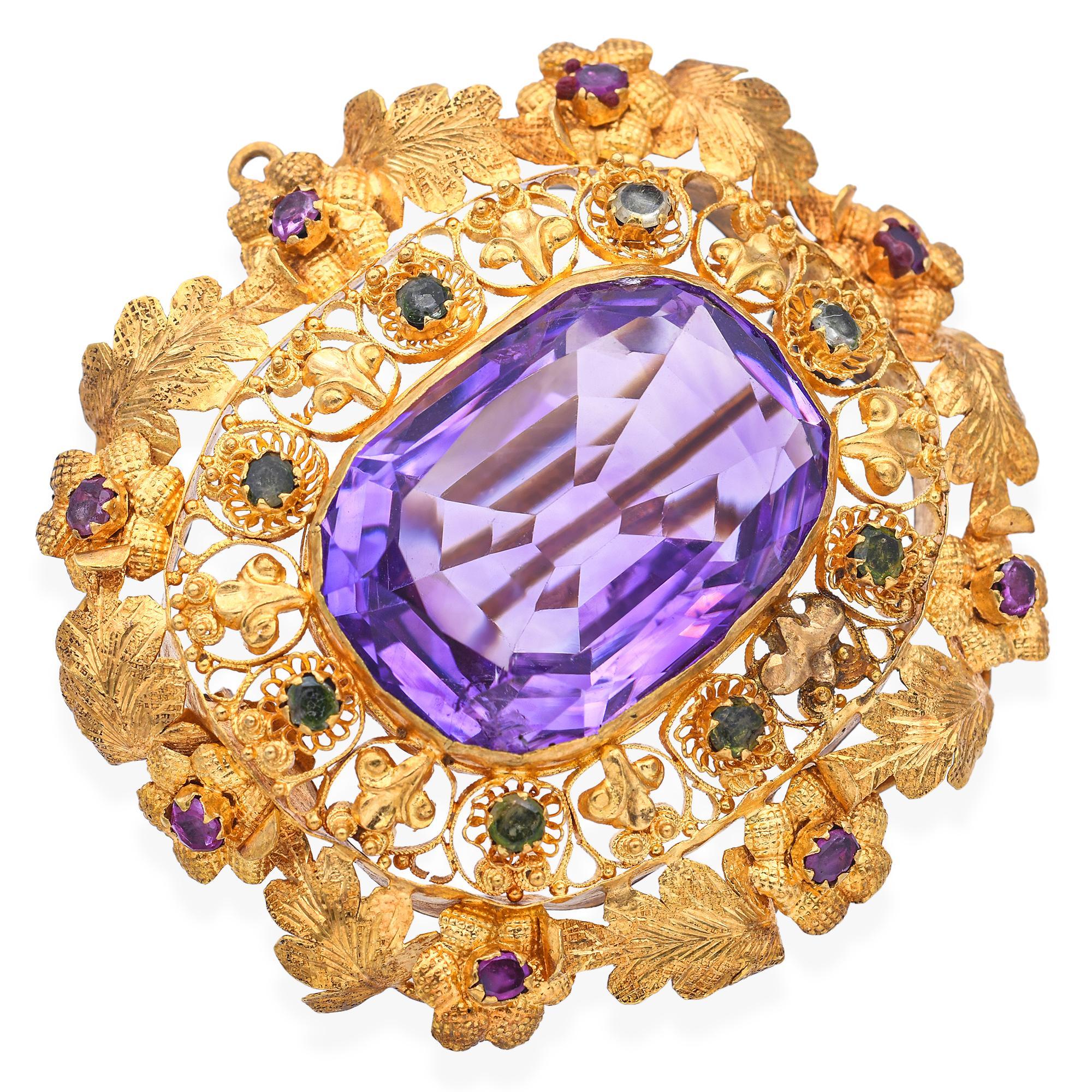 This exquisite antique brooch features a richly hued 22.5ct amethyst as its centerpiece, framed by an elegant arrangement of pink tourmalines and vibrant rubies. Crafted in warm 20k yellow gold, the floral design captures the delicate beauty of
