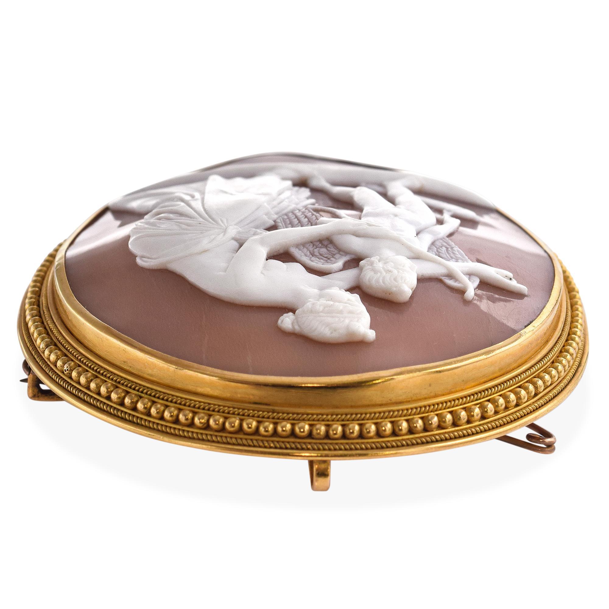 Verdadero tesoro de elegancia clásica, este broche antiguo presenta un camafeo de concha magistralmente tallado a mano que representa a Afrodita, diosa del amor y la belleza, impartiendo sabiduría a su hijo Eros, el dios del deseo. Enmarcada en raro