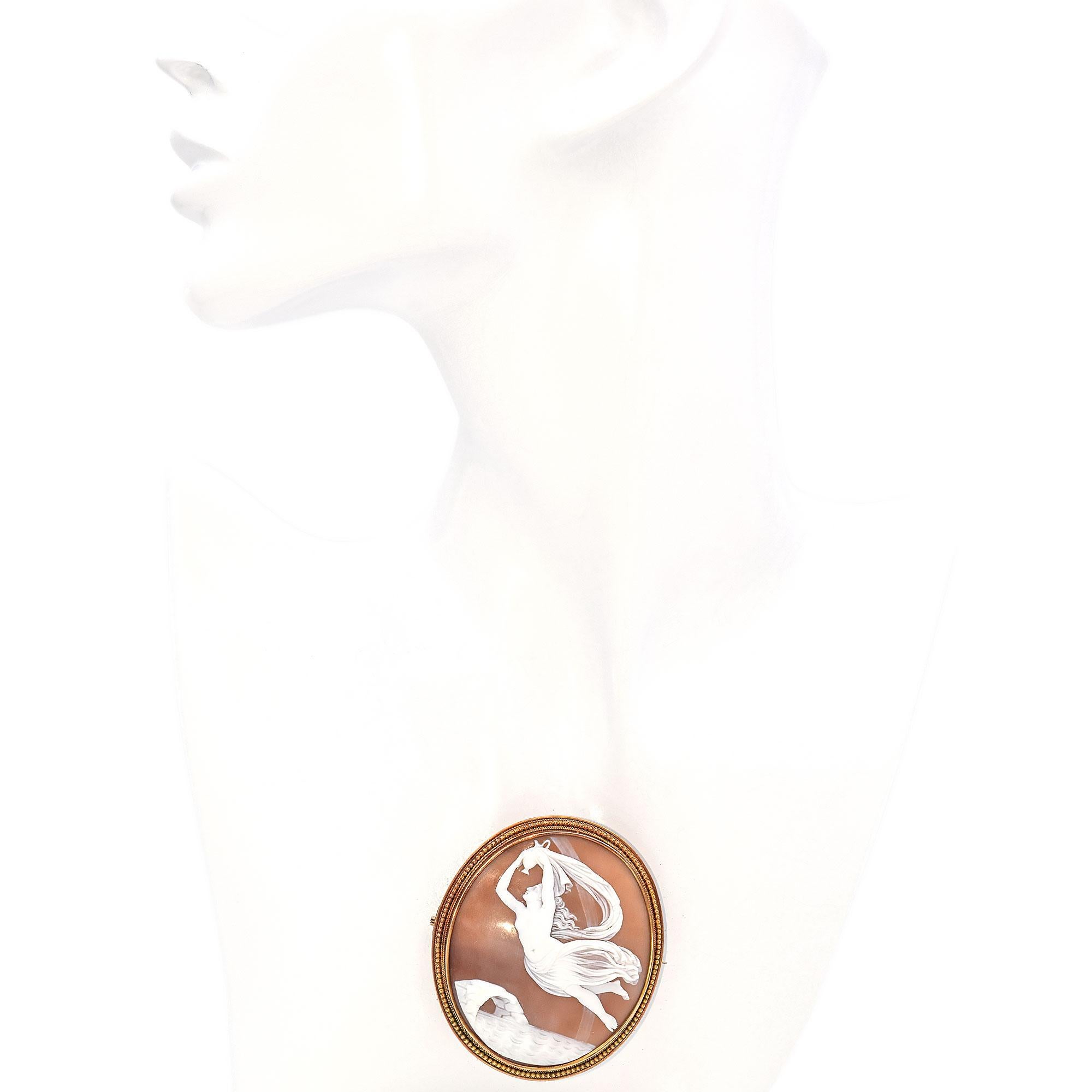 Circa Late 19th Century. This antique brooch showcases a masterfully carved cameo depicting Iris, the messenger goddess, carrying the water of the River Styx to Olympus for the Achilles Heel. The scene is set against a warm background, framed by a