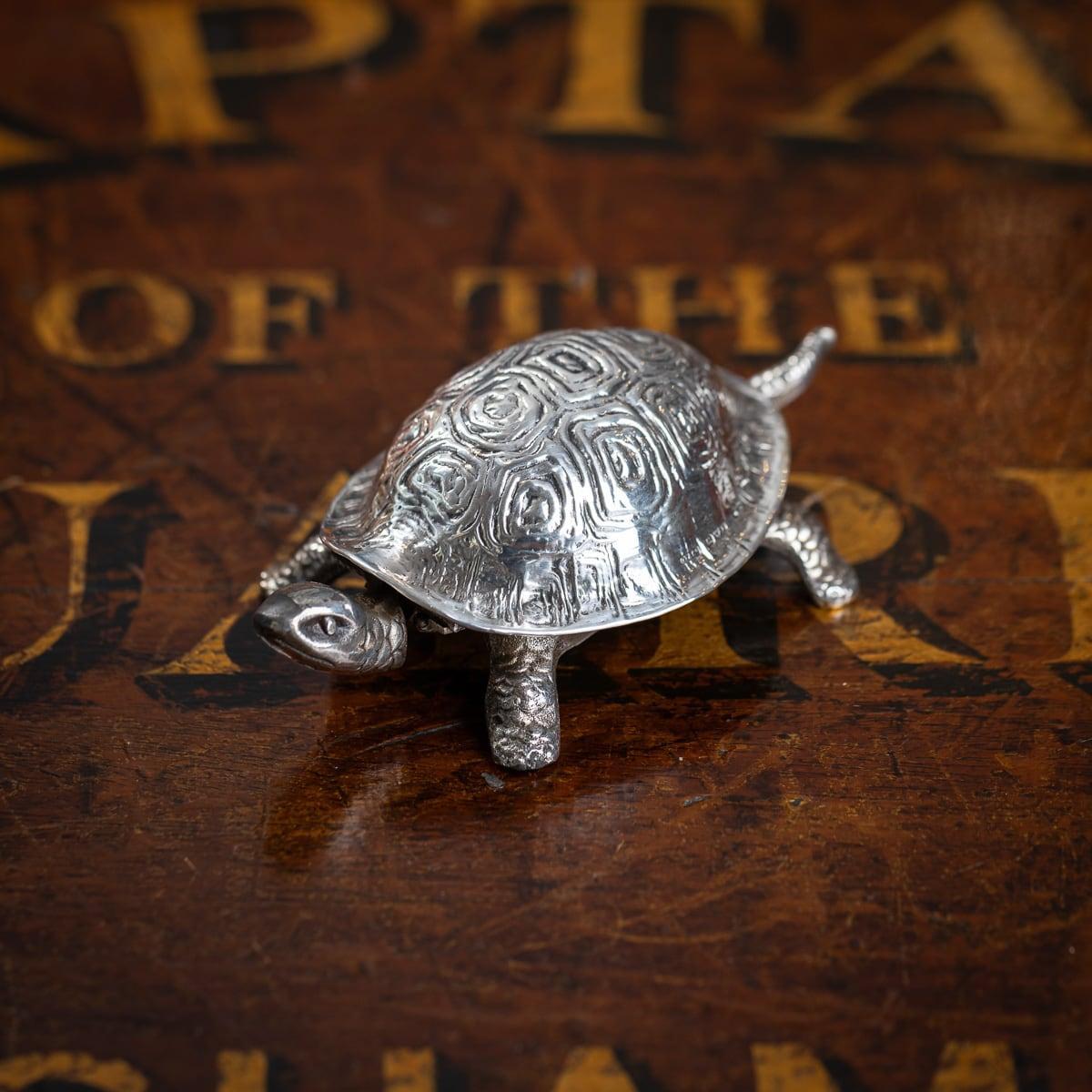 Antique 20th Century English solid silver desk bell crafted in the form of a tortoise. The tortoises' shell is part cast and hand-chased in fine detail. The bell mechanism beneath. Once wound up, the bell can be rung by pressing either the head or