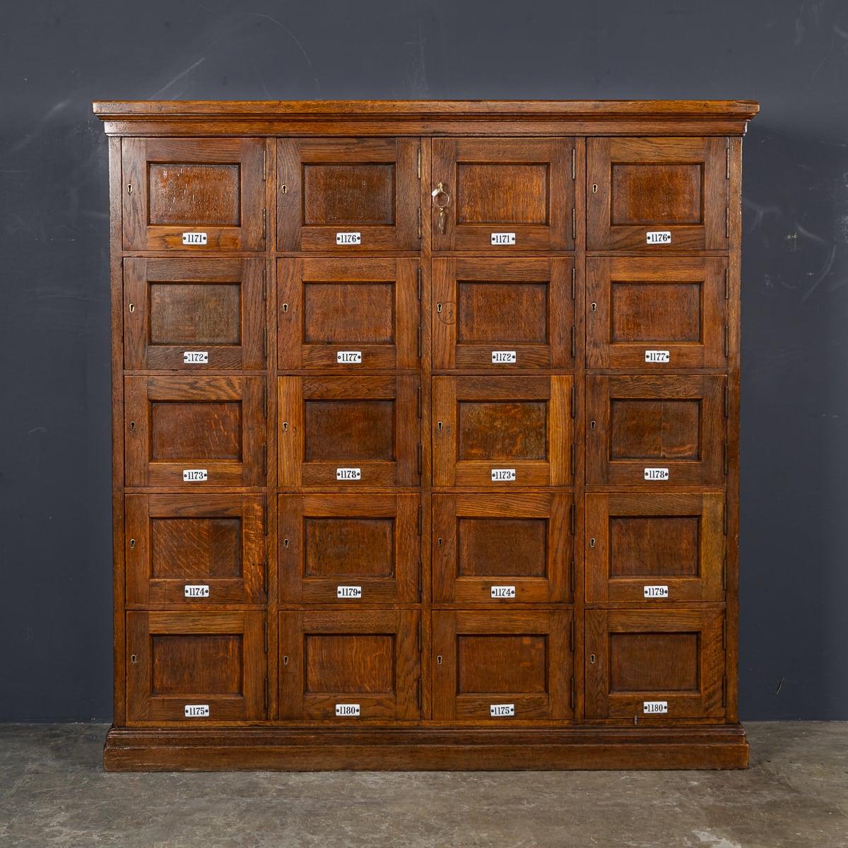 Antique early 20th Century British hand crafted oak estate lockers. This unit would have been undoubtedly used on a large country estate during the 1900's. This piece has twenty cupboards with original brass locks and numbered enamel plates. A