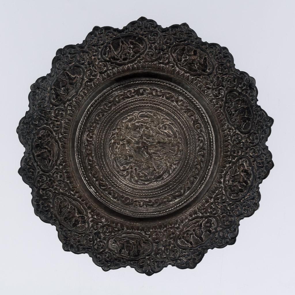 Antique 20th century Burmese solid silver handcrafted repousse' plate, the border and middle repousse' decorated in relief with scenes from the Burmese mythology amongst scrolling foliage. The dish is not hallmarked, but has been acid tested and