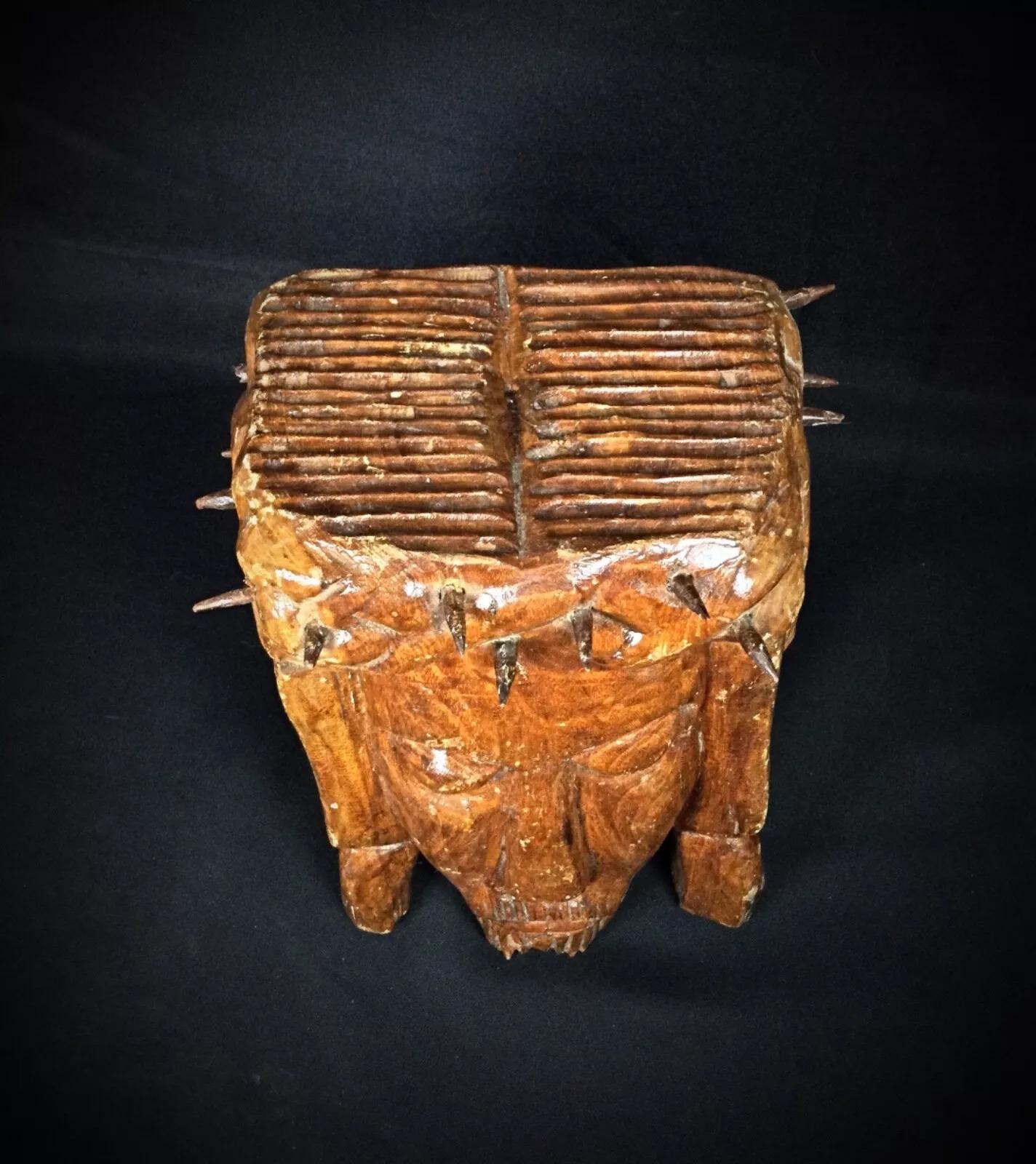This antique carved wooden depiction of Christ's face with a crown of thorns dates back to the 20th century. It is in good condition, with one thorn missing and another broken. The wood would benefit from refinishing, and there is slight wear on the