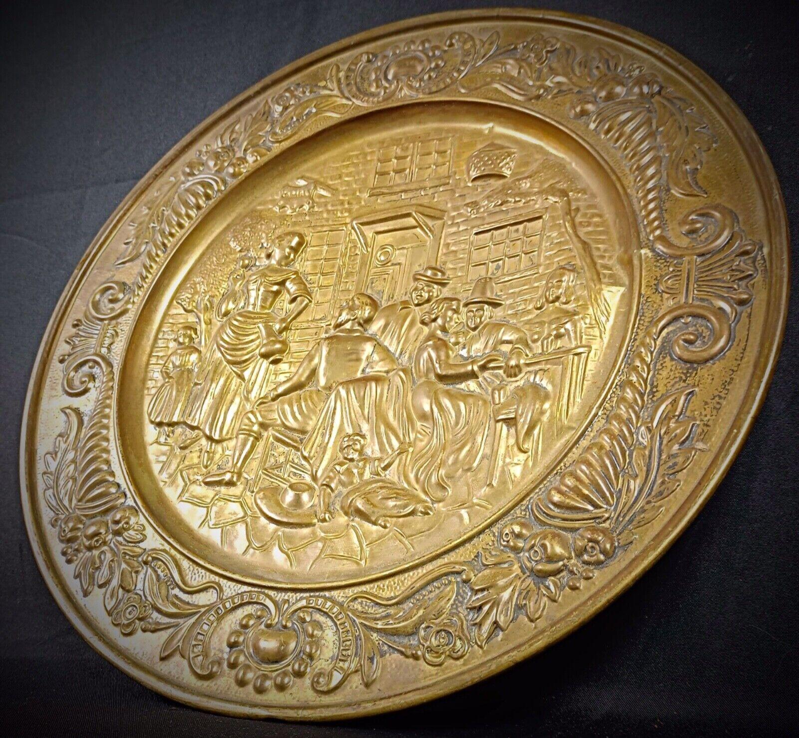 Add a touch of historical charm to your decor with this antique 20th-century decorative brass plate, featuring a beautifully detailed repoussé scene of a lively tavern. The intricate craftsmanship captures the essence of traditional gatherings,