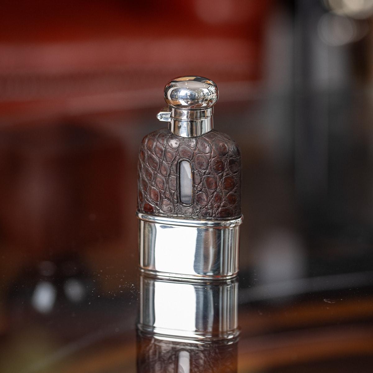Antique early-20th Century Edwardian solid silver, blown glass and bound in sumptuous crocodile leather hip flask, of rounded rectangular form, with a pull off cup, top mounted with a hinged and screw lid. Hallmarked with English silver (925