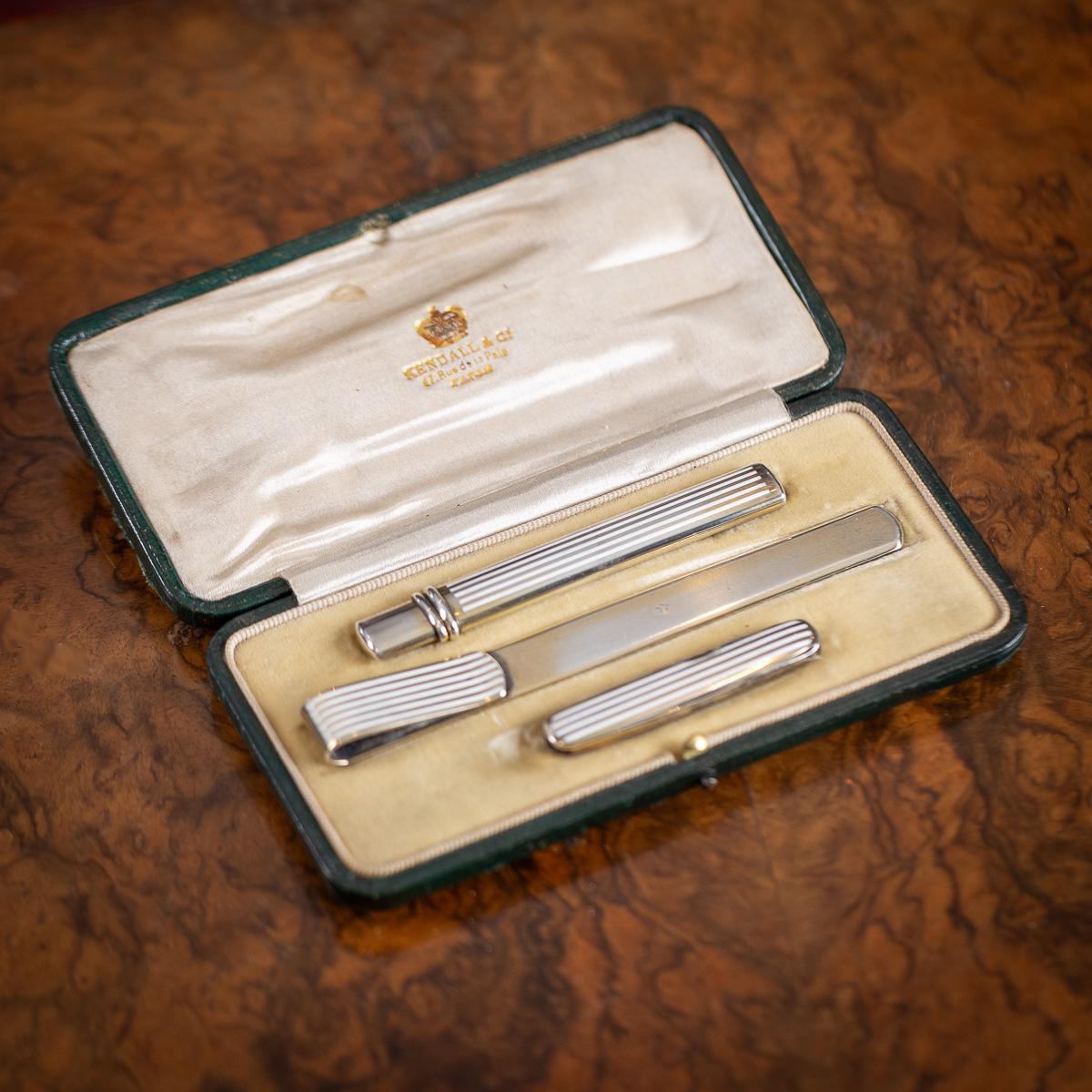 Antico set da scrivania inglese del XX secolo in argento massiccio dorato e smalto, composto da matita, tagliacarte e coltellino. Ogni pezzo è decorato con smalto bianco intarsiato e la matita riflette un design generale che ricorda lo stile