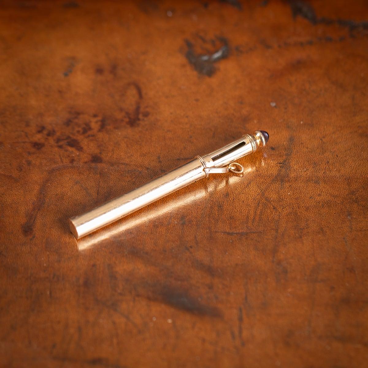 Antique 20th Century possibly French 14ct gold retractible pencil. Designed to be attached to a key chain or as a pendant, this pencil features a blue cabochon sapphire decorative tip which is covered by the hinged chain link. Upon pulling the