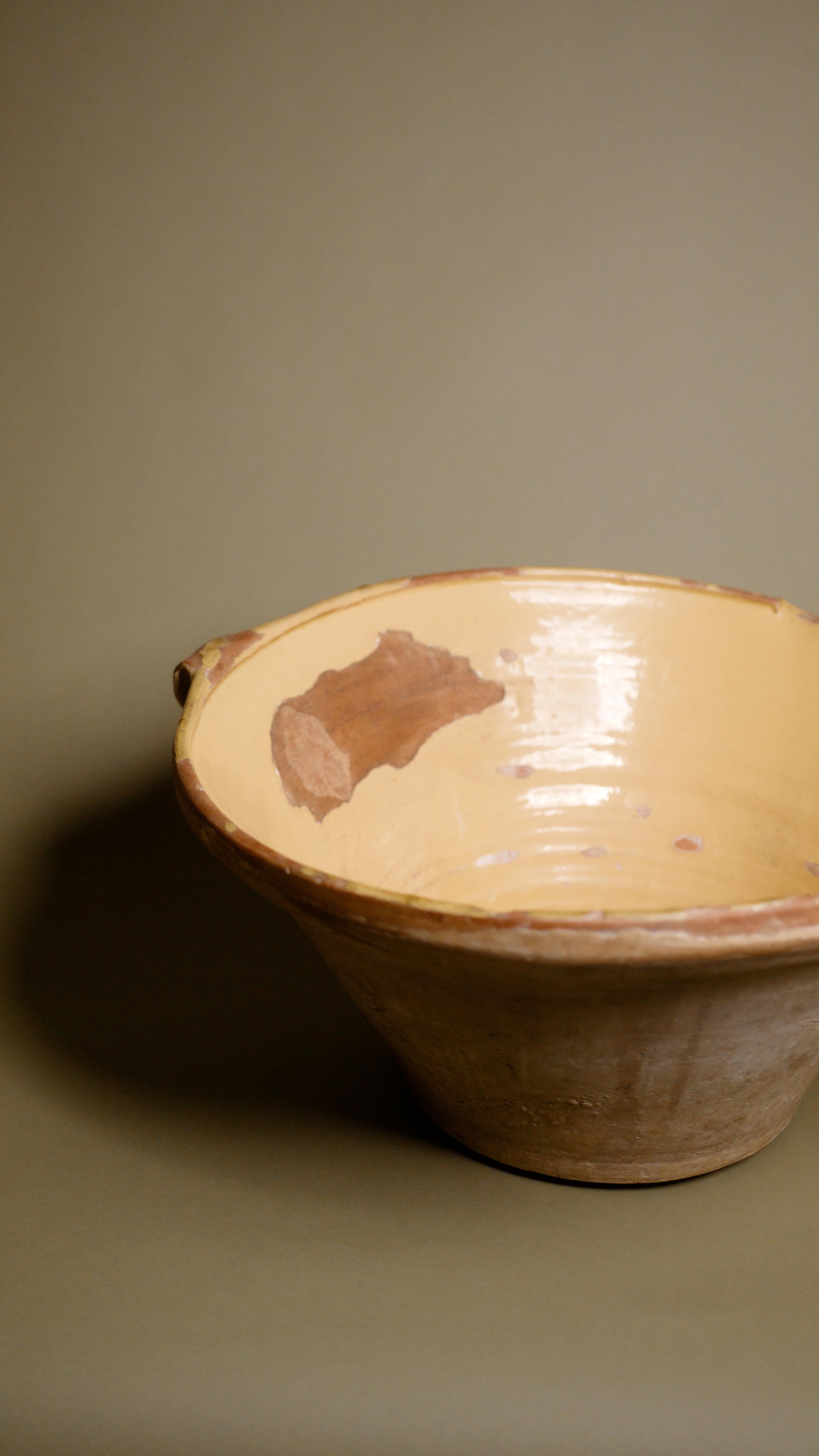 Cette ancienne coupe française en terre cuite du 20e siècle est une pièce remarquable du patrimoine européen de la poterie, incarnant le charme rustique des cuisines provinciales françaises. Fabriqué à la main selon des techniques de poterie