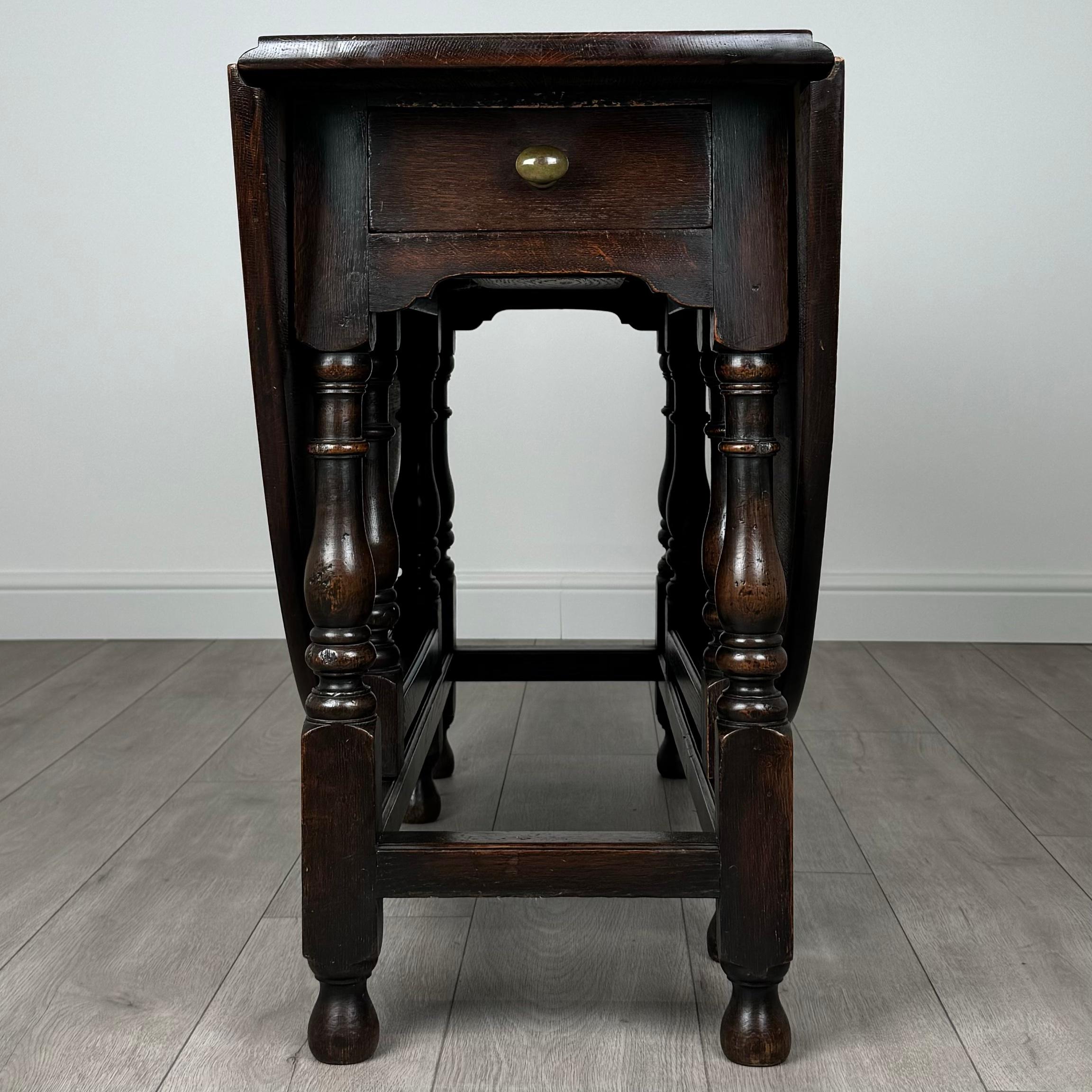 Cette charmante table ancienne à piétement en chêne du XXe siècle est une pièce polyvalente et magnifiquement conçue, parfaite pour ajouter de la chaleur et de la fonctionnalité à n'importe quelle pièce. 
Posée sur des pieds élégamment tournés