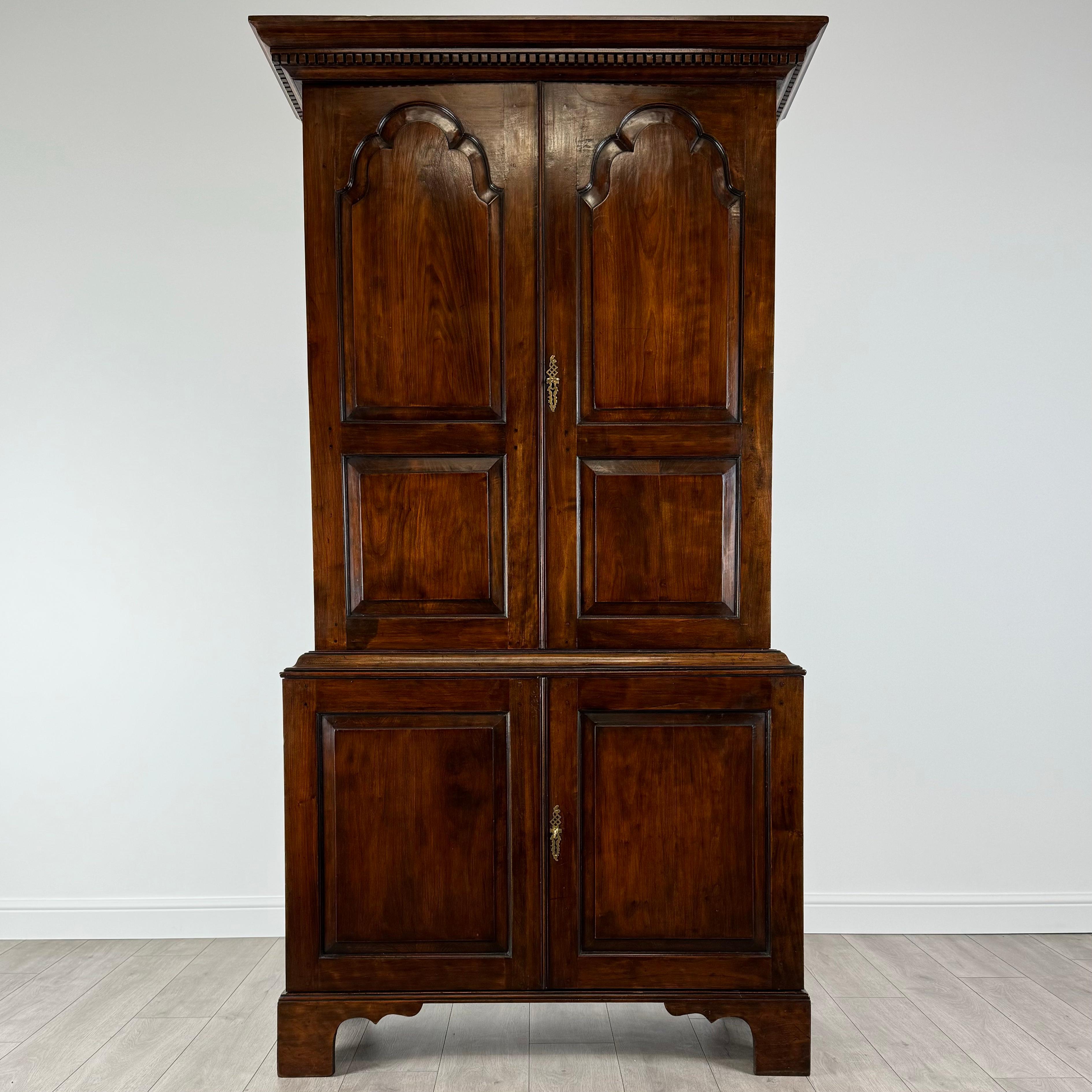 Este antiguo armario de estilo georgiano del siglo XX, fabricado en madera de frutal, es una asombrosa representación de elegancia atemporal y artesanía excepcional. 
Su diseño capta maravillosamente la esencia del mobiliario georgiano, con cuidados