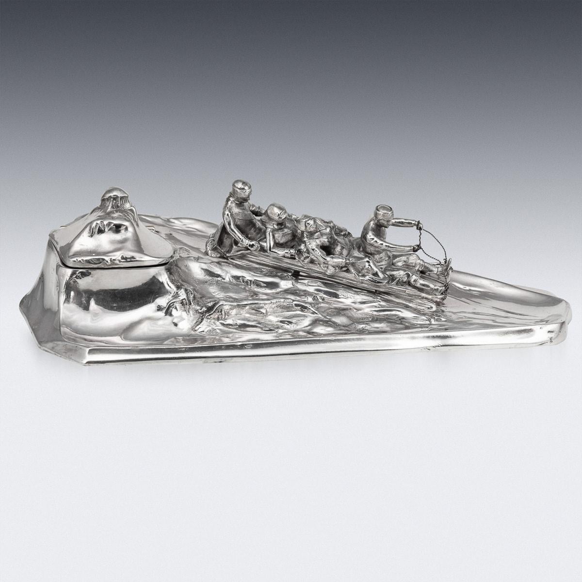Antique 20th Century German silver plated inkwell depicting a group of children on a toboggan sliding down the mountain, under one of the mountain peaks is a glass lined inkwell. A fabulous item to add as a desk accessory. Stamped on the underneath