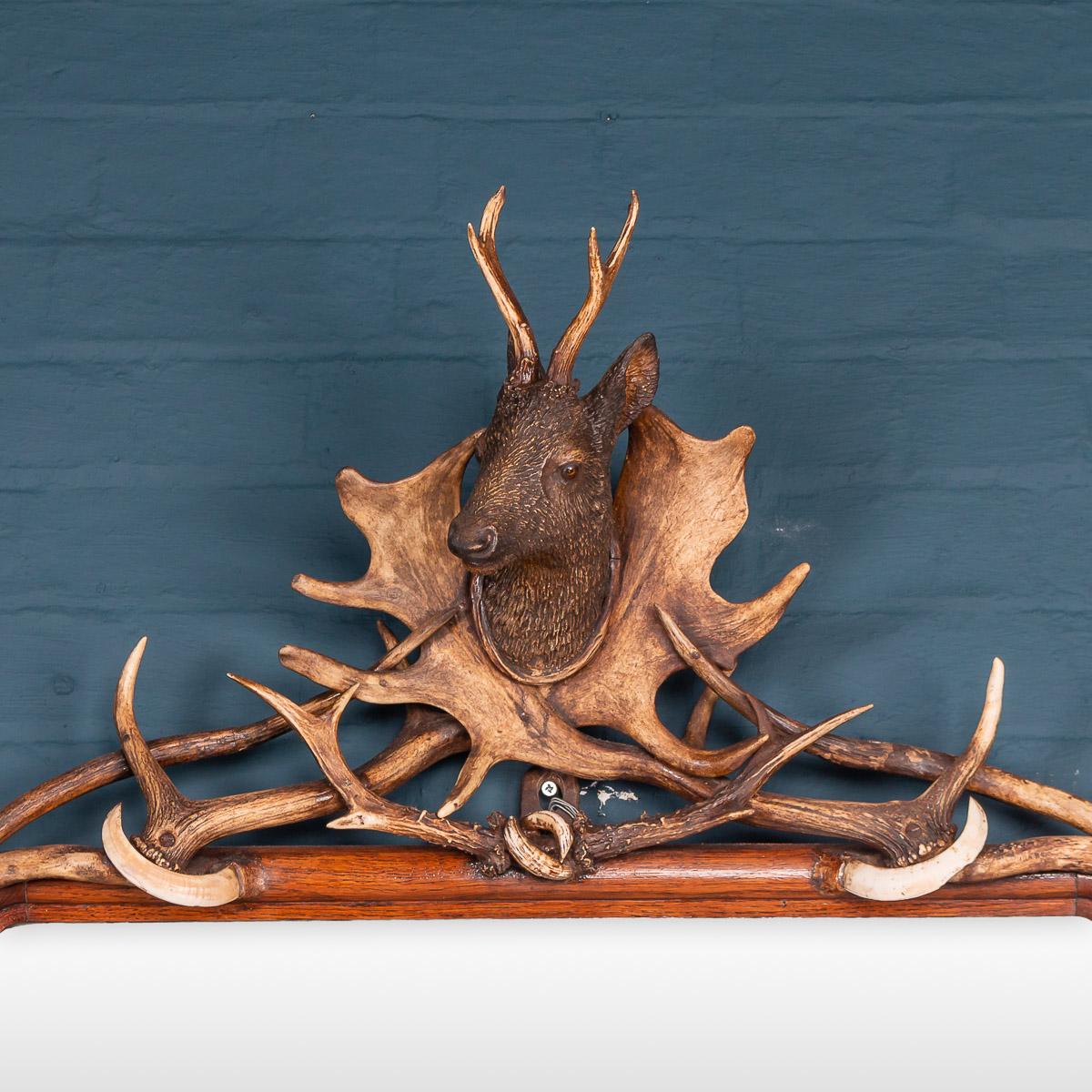 An extremely unusual hall mirror dating to the latter part of the 19th century or early 20th century. Original mercury mirror, the wood frame decorated with carved black forest animals in softwood, antler horns and ivory boar