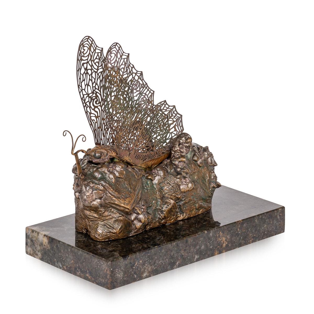 Papillon en bronze métamorphique peint et doré du début du XXe siècle, réalisé par l'Autrichien Carl Kauba (1865 - 1922). Il s'agit d'un papillon perché sur une base feuillue, qui s'ouvre pour révéler une fée nue. Les ailes sont articulées grâce à
