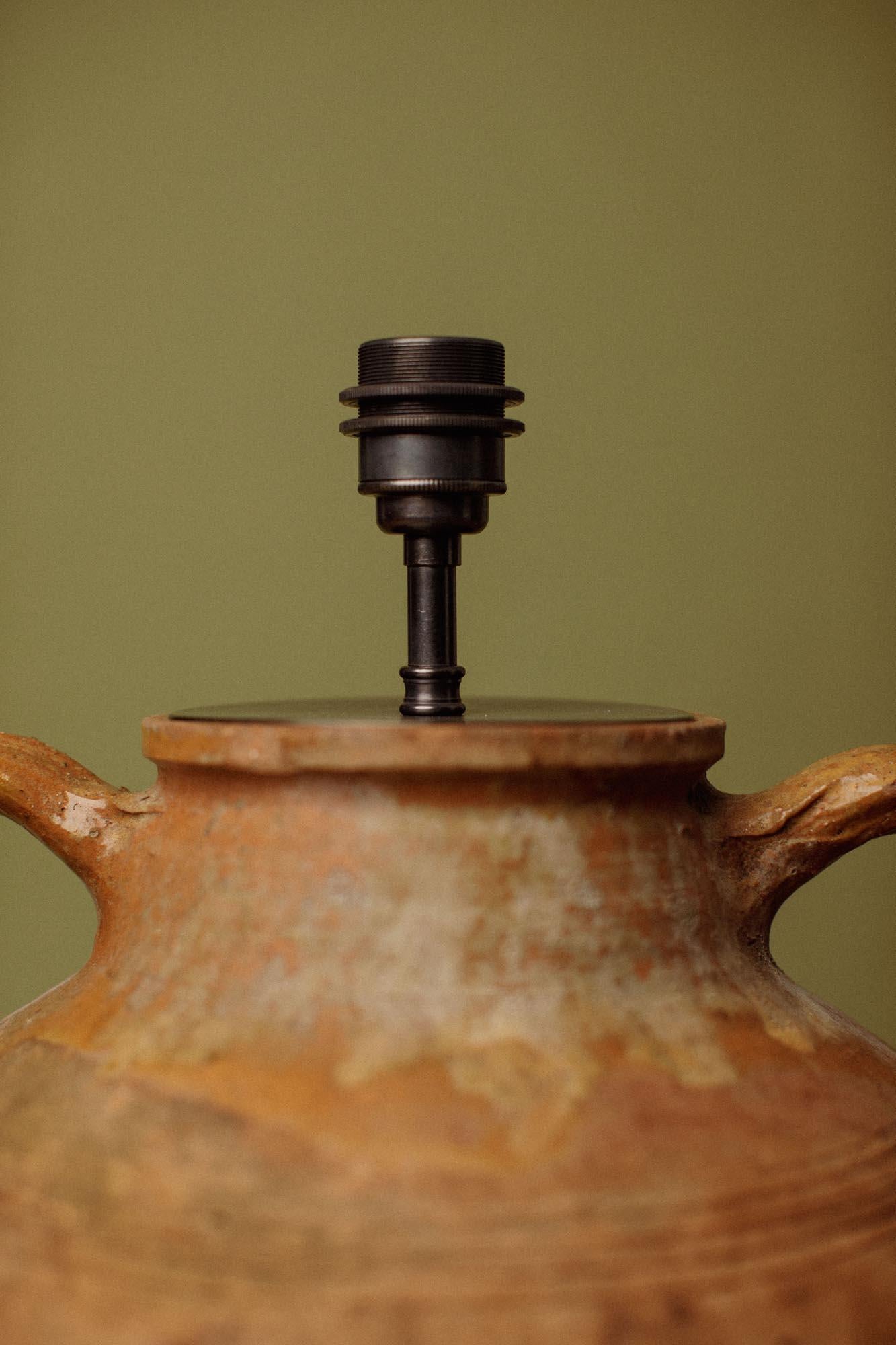 Cette jarre en terre cuite cultivée à la main, produite à l'origine dans l'ouest de la Turquie près d'Izmir pour conserver l'huile d'olive fraîchement pressée, a été transformée avec sensibilité en lampe de table. Formée à partir d'argile rouge