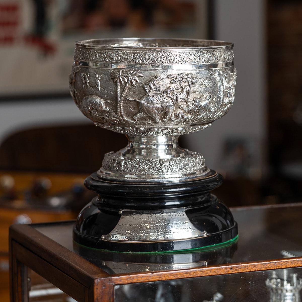 Antique early 20th-century Indian (Lahore / Poona) solid silver bowl on stand, designed in a traditional shape with a large domed foot, resting on a large ebonised presentation stand. The bowl features intricate and ornate embossing, with a top band