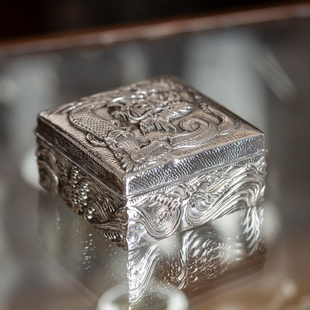 Antique early-20th Century Japanese Meiji period solid silver cigar box. The sides and lid feature high-relief embossing of water and dragons, adorned with flowing whiskers on a hand-hammered surface. The interior is lined with dark wood, including