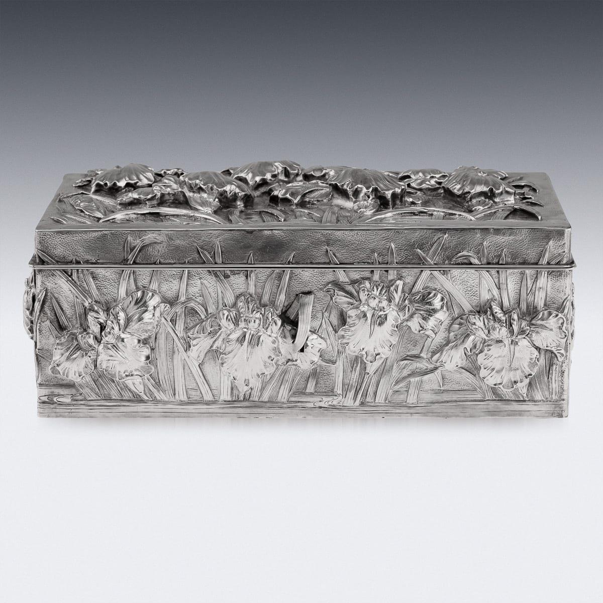 Antique early 20th Century Japanese Meii period solid silver cigar box of rectangular form, double walled and finely decorated in high relief with iris flowers emerging from water, set against a hand-hammered ground. The hinged lid opens to reveal
