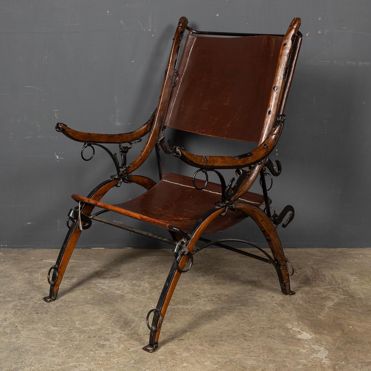 A strikingly unique chair, crafted around the turn of the 20th Century, fashioned from carriage harness holders with a leather seat and backrest. This distinctive piece showcases ring hooks on the armrests and legs, originally designed to tether a