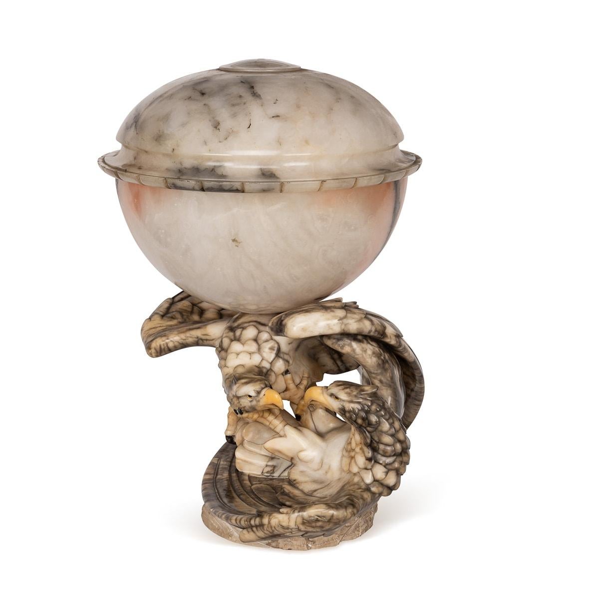 Antique early 20th Century Exquisite eagle table lamp meticulously handcrafted from two solid alabaster pieces, capturing a dynamic scene of two eagles in combat, featuring intricately detailed glass eyes. When illuminated, it emanates a gentle,