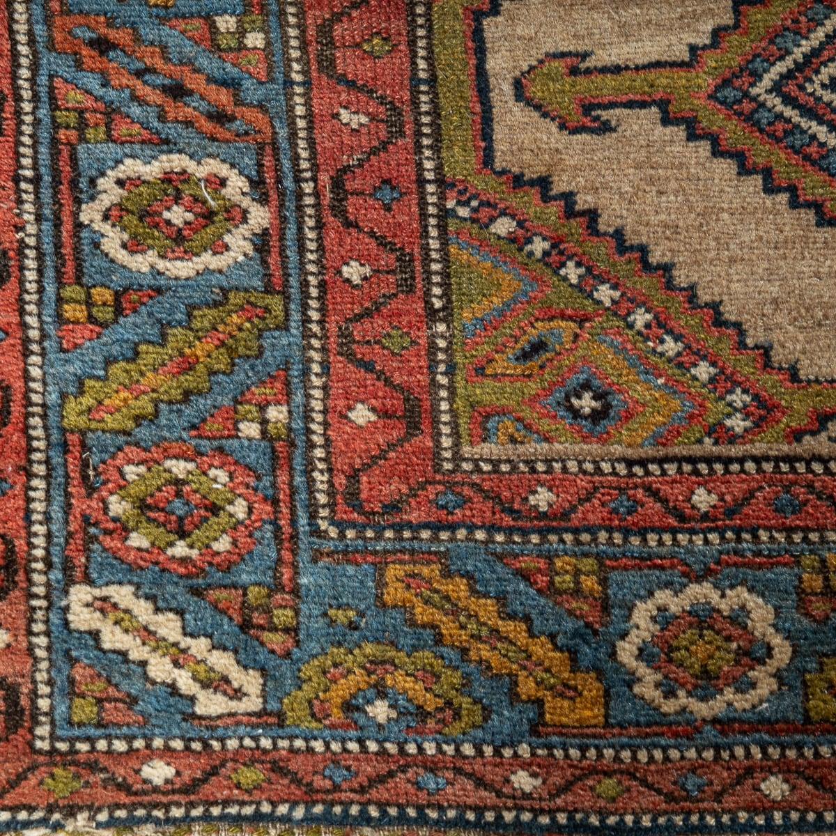 Ancien tapis de course persan Hamedan fait à la main au début du 20e siècle. Confectionné dans un mélange de laine de chameau, ce chemin de table présente un design unique avec cinq médaillons dans le motif central, encadré d'une bordure bleue. Les