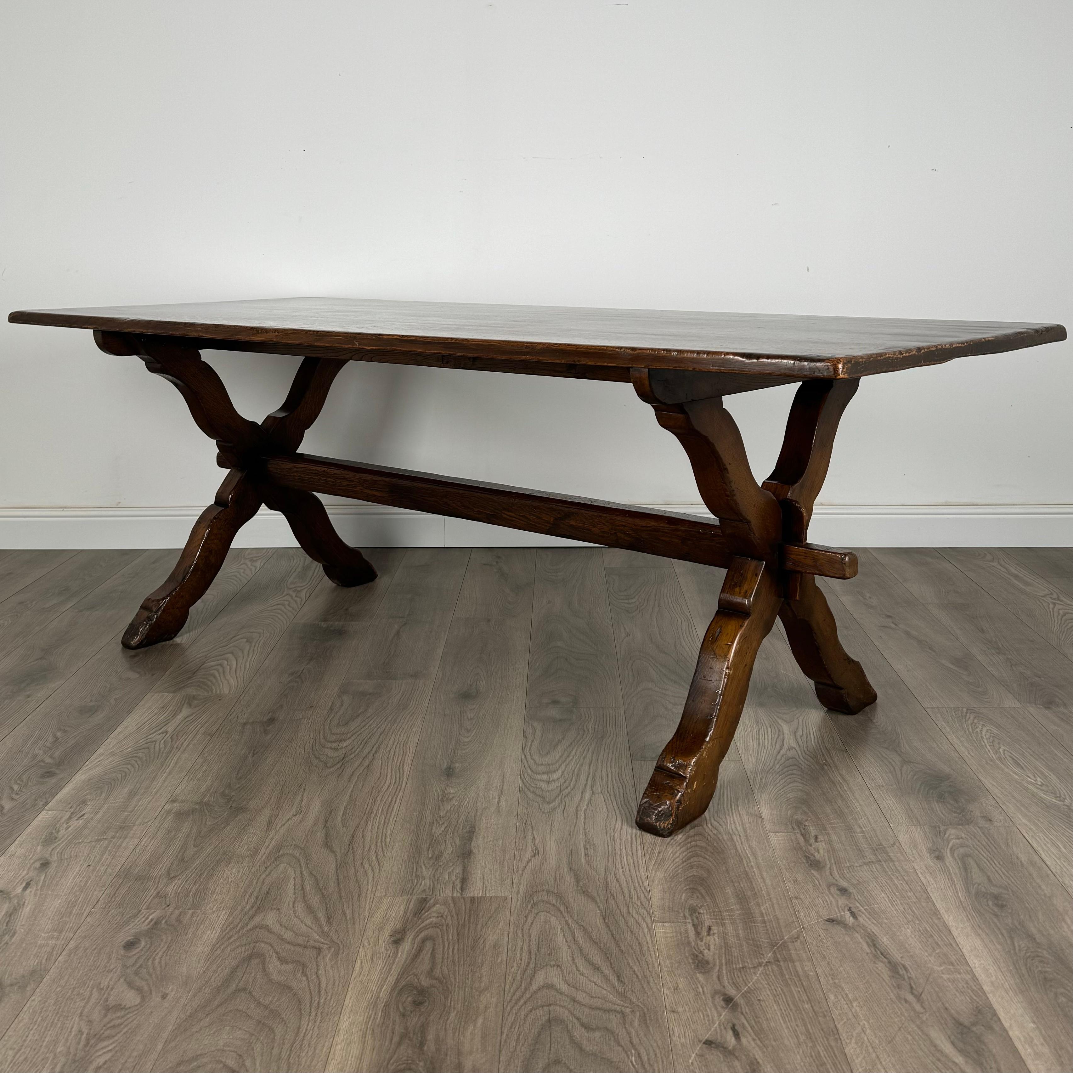 Table de salle à manger ancienne du XXe siècle, de style réfractaire, en chêne massif, témoignant d'un savoir-faire de la plus haute qualité. Il est doté d'un brancard central qui lui confère une stabilité accrue et une touche traditionnelle. La