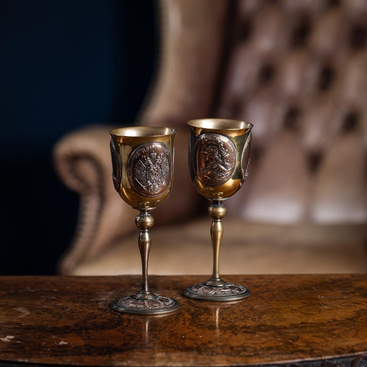 Antique 20th Century Russian World War I commemorative goblets, attributed to the House of Fabergé. They are crafted from a combination of copper and brass, featuring a distinct neoclassical profile with flared bowls, baluster stems, and broad,
