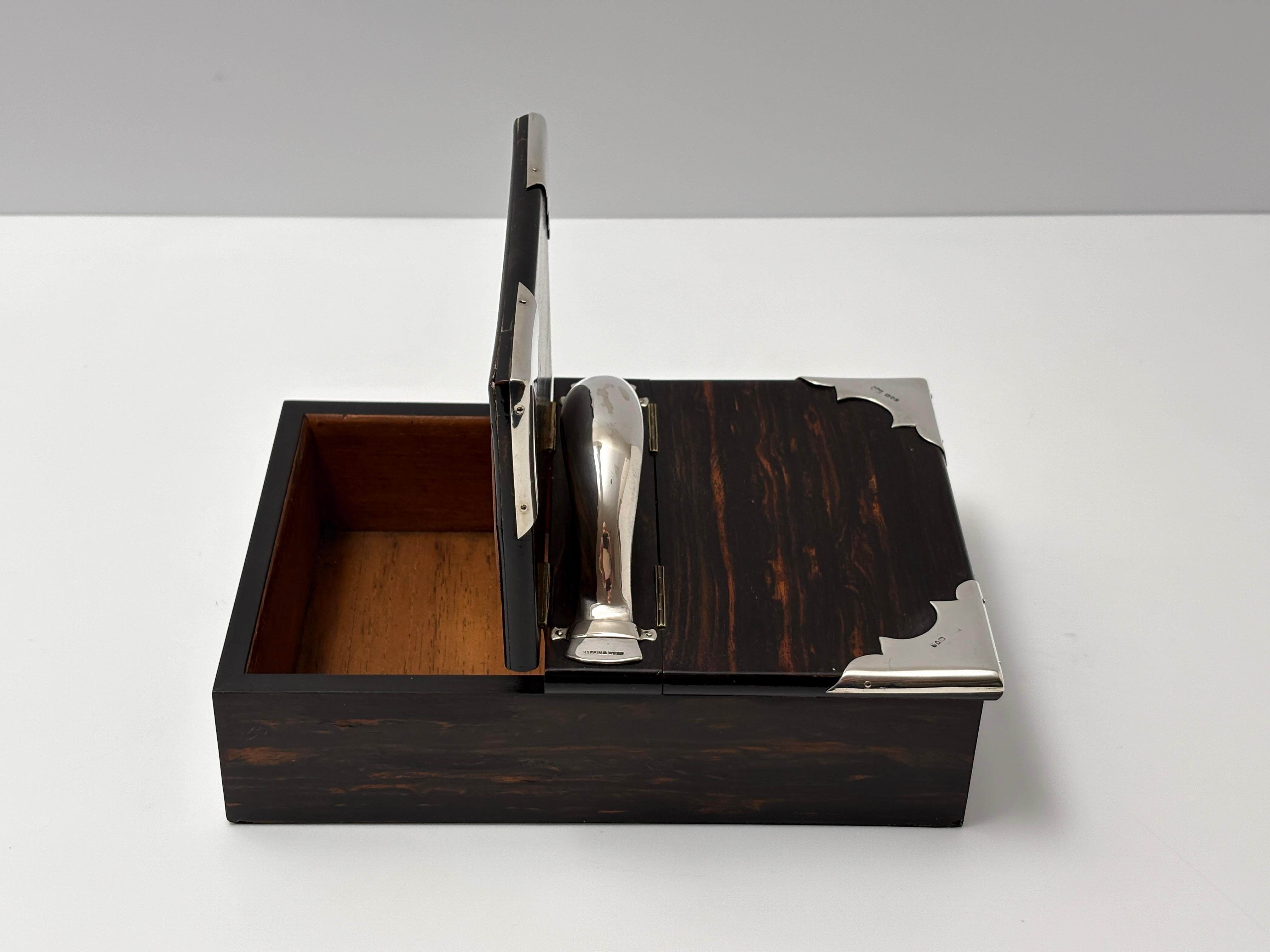 Caja para puros antigua del siglo XX en madera de Coromandel y plata de ley
Fabricante Mappin & Webb Fecha Londres 1901.

El color intenso de esta pieza resalta sobre la plata. La caja está en excelente estado, las esquinas y el asa de plata tienen