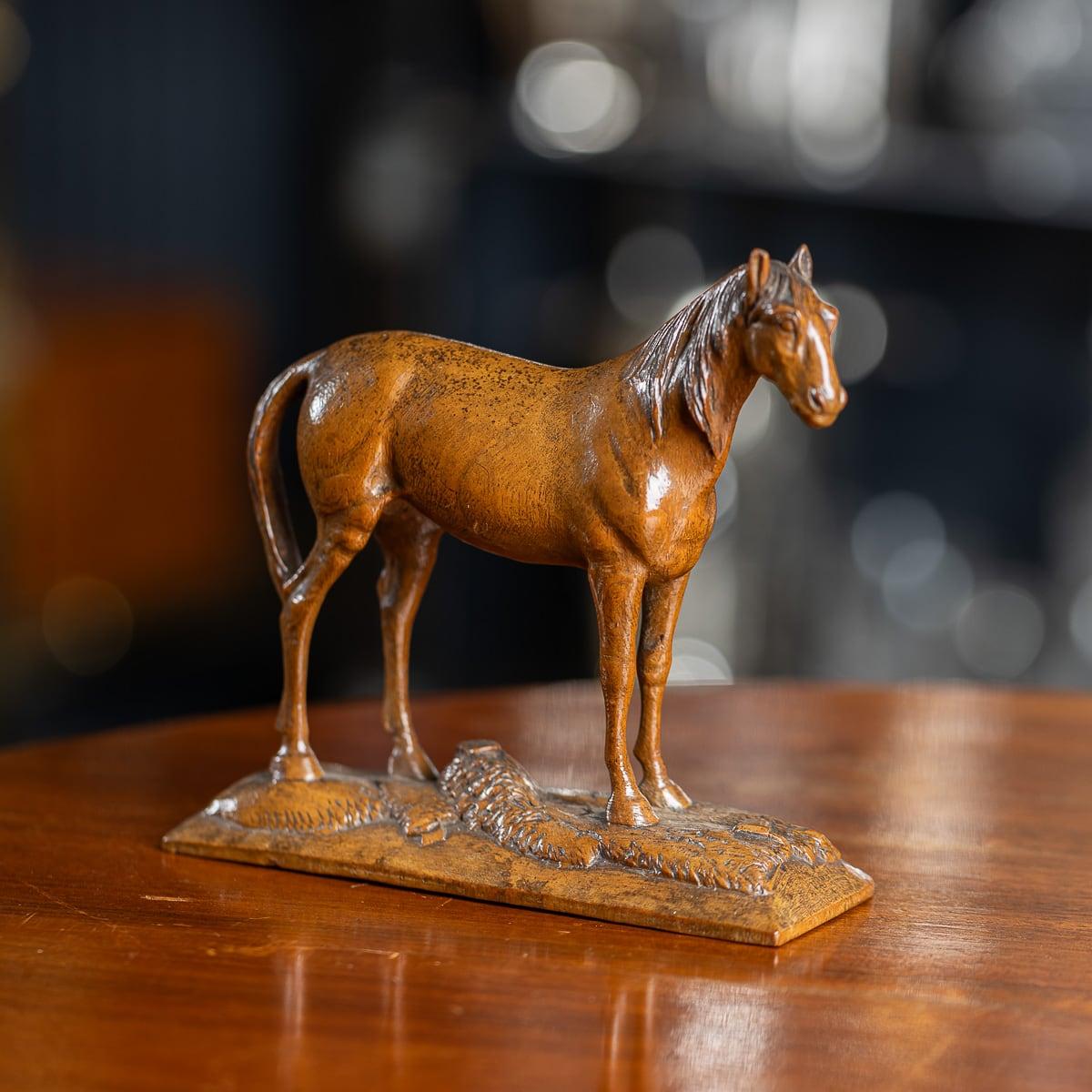 Cheval ancien début 20ème siècle Victorien en bois massif. Sculpté de manière experte dans un morceau de noyer, ce cheval remarquable se dresse fièrement sur une base en bois. Son design intemporel lui permet de s'intégrer parfaitement dans les