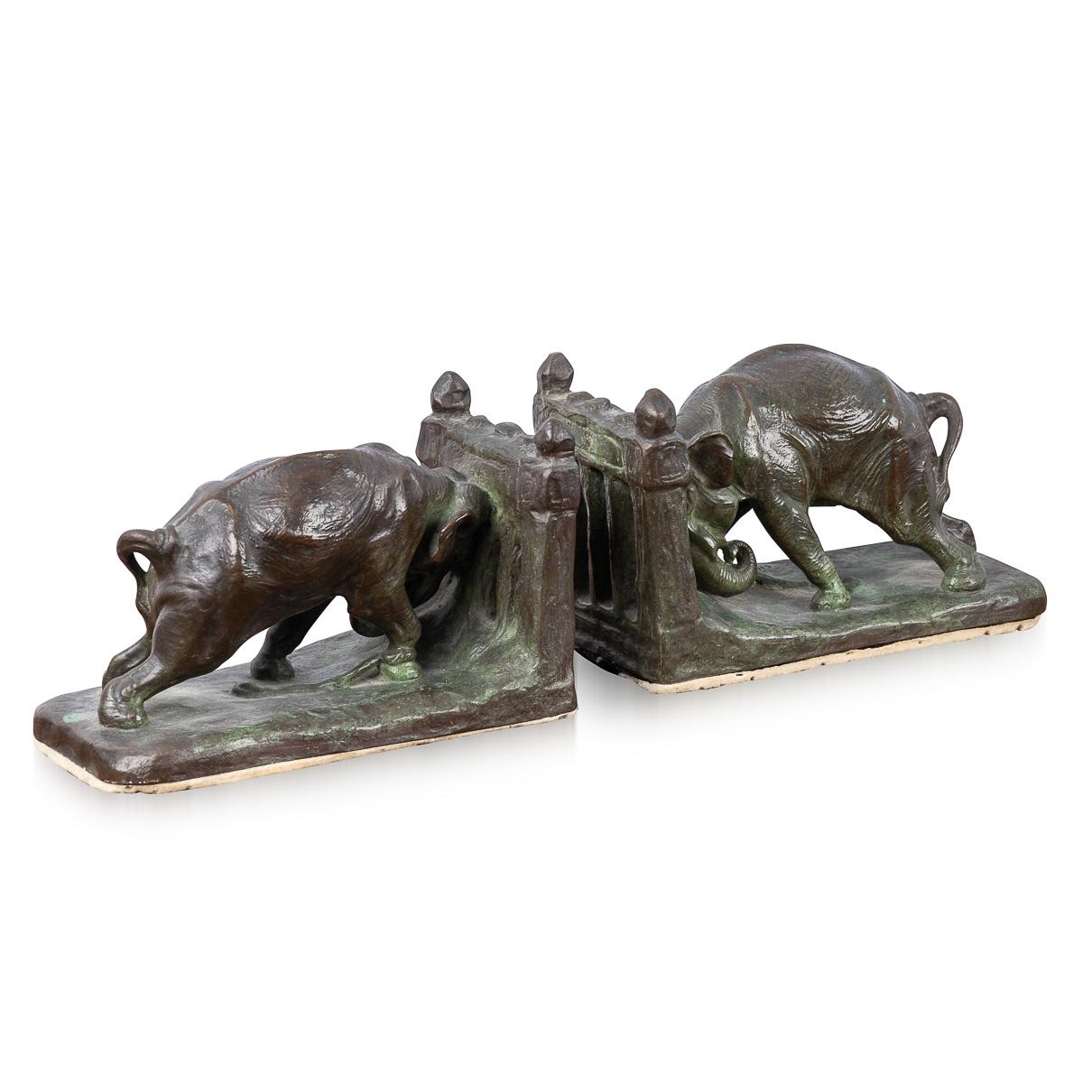 Antique early 20th Century American Art Deco bronze book ends, realistically cast as two elephants pushing against a gate. The book ends are signed 