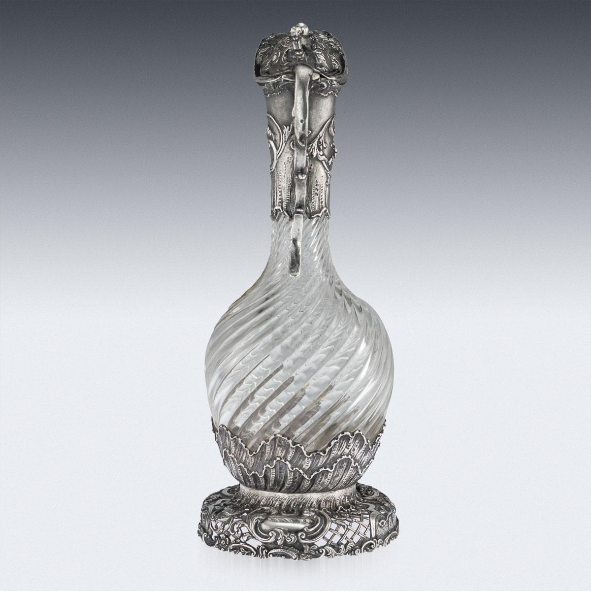 Antique 20th century Dutch solid silver mounted glass wine claret jug, swirl glass body applied with silver scrolling foliage and flowers, set with a hinged lid, applied with a thumbpiece and an elaborate scroll handle.

Hallmarked with a Dutch