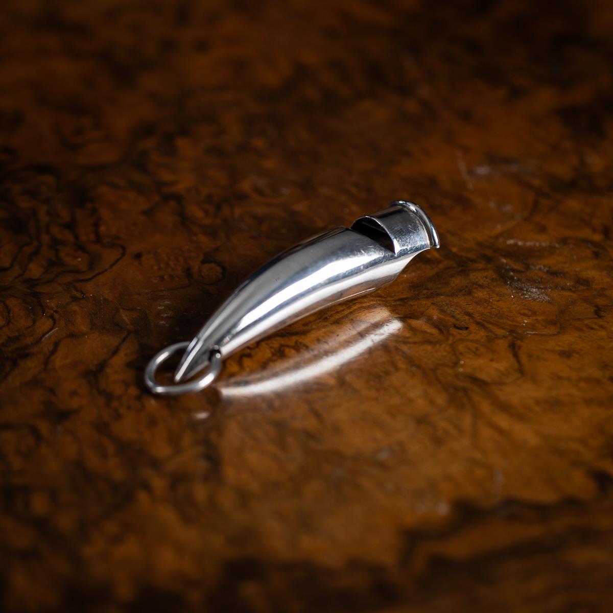 Antiguo silbato de caza inglés de plata maciza del siglo XX. Utilizada durante las cacerías o llevada en cadenas de reloj, esta pieza tiene una anilla de suspensión en el extremo estrecho para engancharla a una cadena o chatelaine. Plata maciza