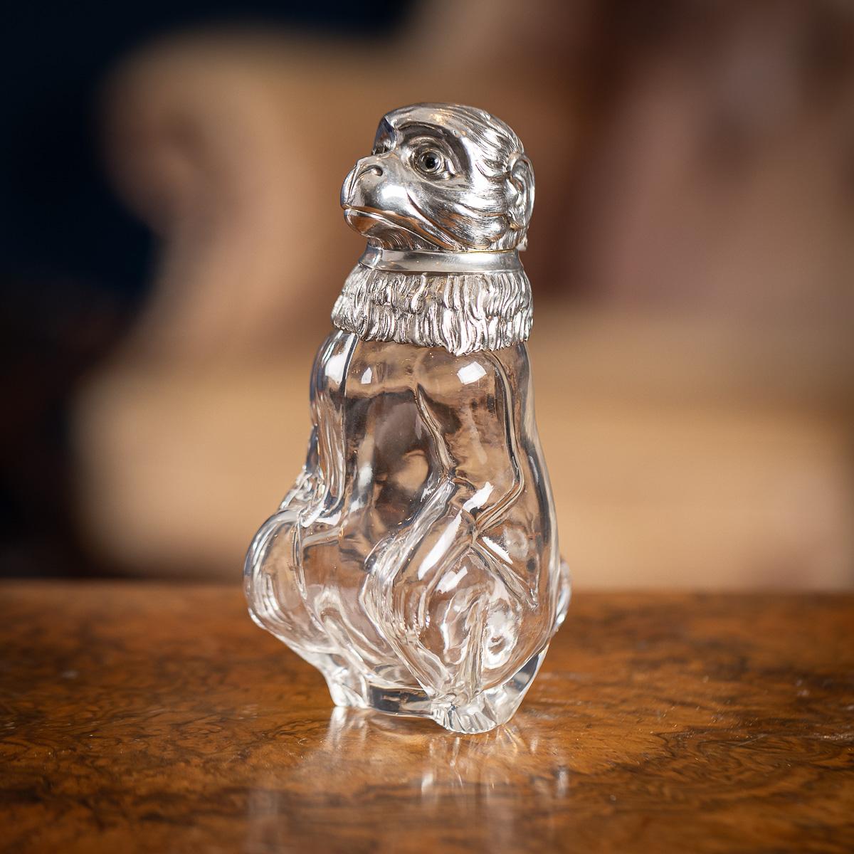 Ancienne cruche à claret en forme de singe en argent massif et en verre, datant du début du 20e siècle. La carafe présente un corps en verre méticuleusement travaillé, dont la forme rappelle celle d'un singe assis, ses pattes avant reposant sur ses
