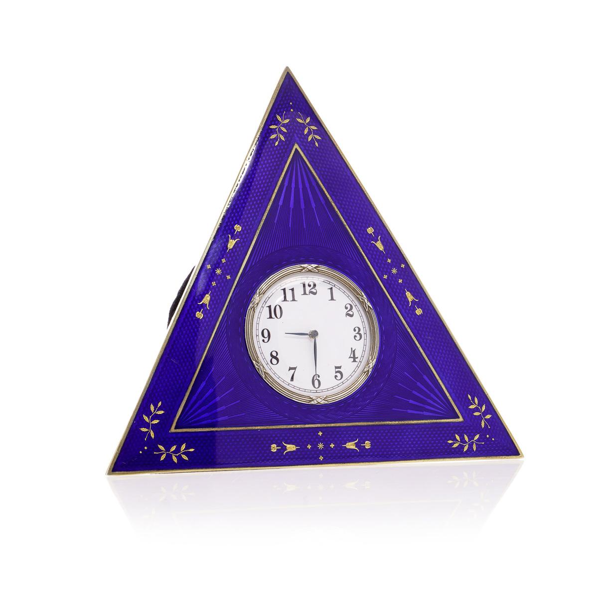 Orologio da tavolo norvegese in argento dorato e smalto guilloché di David Andersen. Questo pezzo presenta un piccolo quadrante circolare incastonato in una cassa triangolare in smalto blu, tornita a motore e ornata da delicati dettagli di foglie