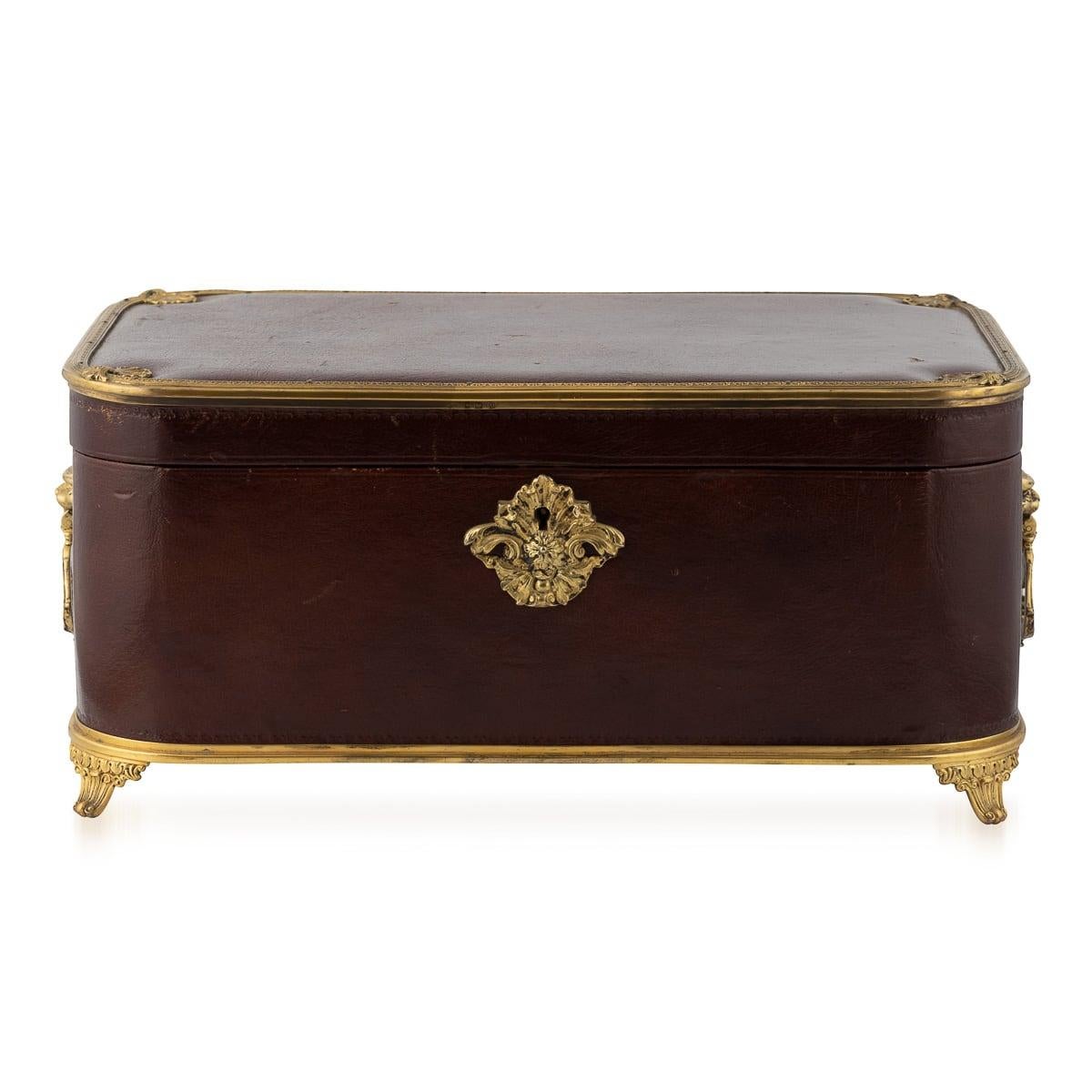 Antique early 20th Century British burgundy leather-bound jewellery box with decorative silver-gilt mounts, cast escutcheon and lion mask handles. It features a working lock and a key. Inside, the soft beige silk lining holds three trays: one with