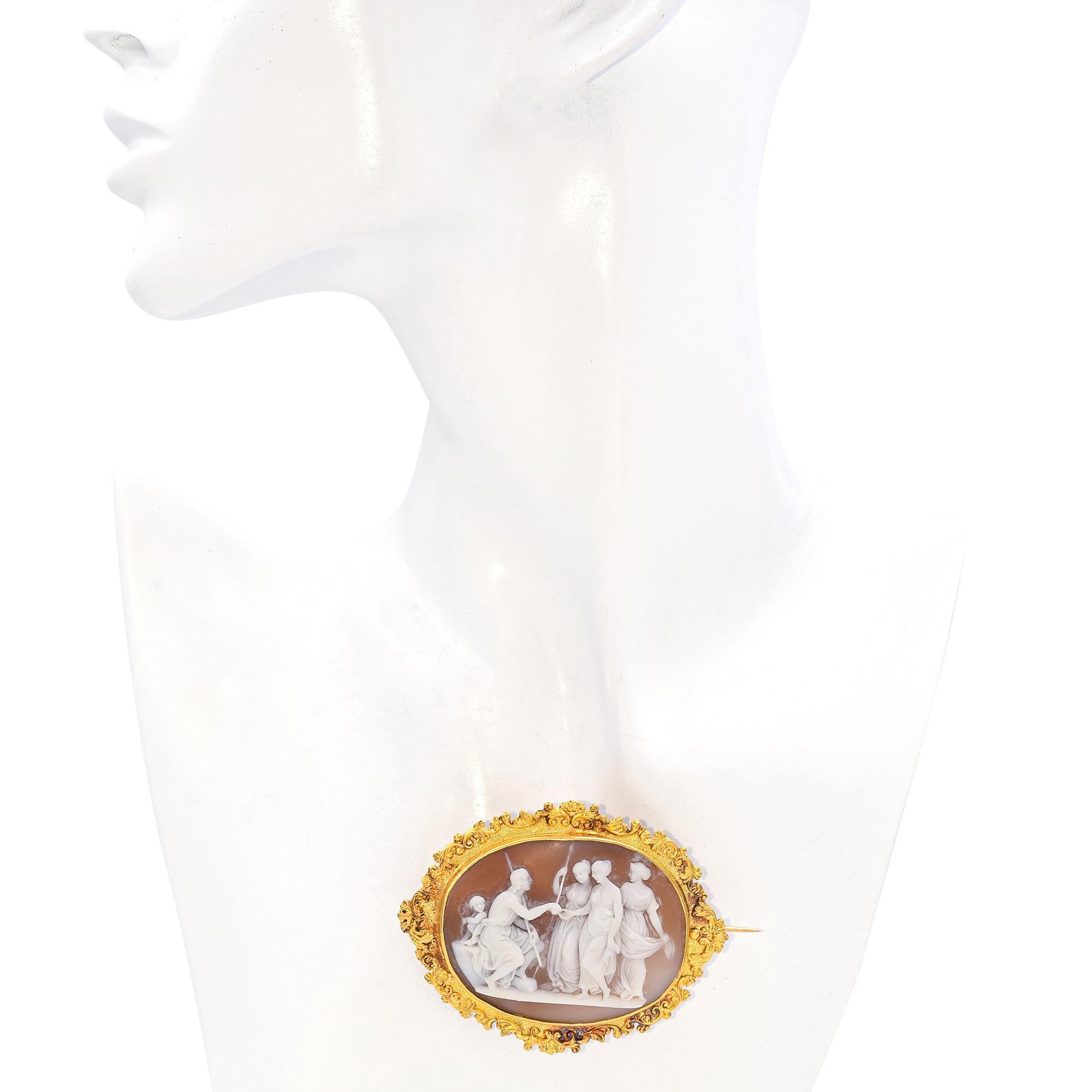 The cameo brooch is an exquisite piece of jewelry, featuring a delicate and ornate yellow gold frame that is richly adorned with elegant scrolls. The scrolling design around the edges of the frame creates a sense of movement and adds a touch of