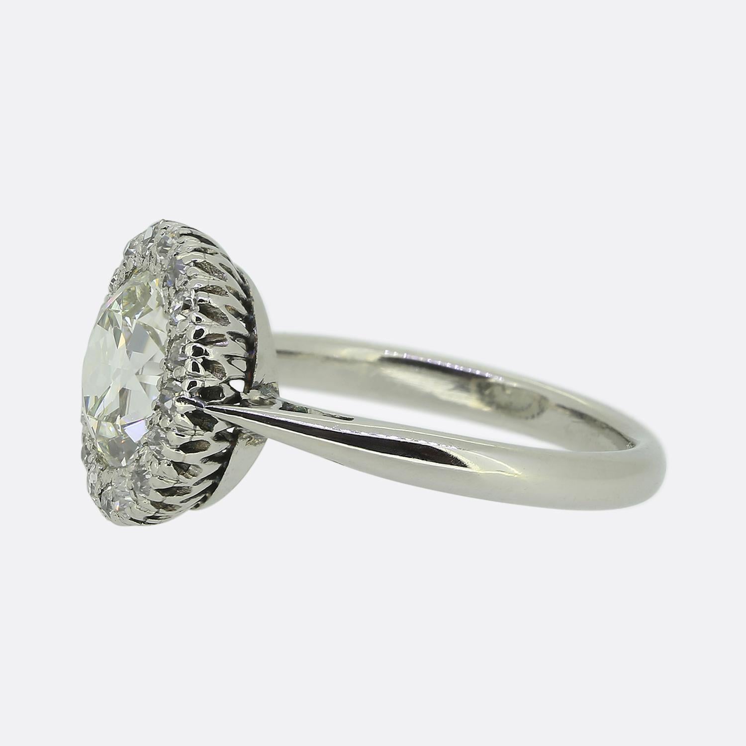 Hier haben wir einen atemberaubenden, aus Platin gefertigten Diamant-Cluster-Ring. In der Mitte der Vorderseite befindet sich ein beeindruckender runder, facettierter Diamant mit altem europäischem Schliff, der in einem bezaubernden weißen Farbton