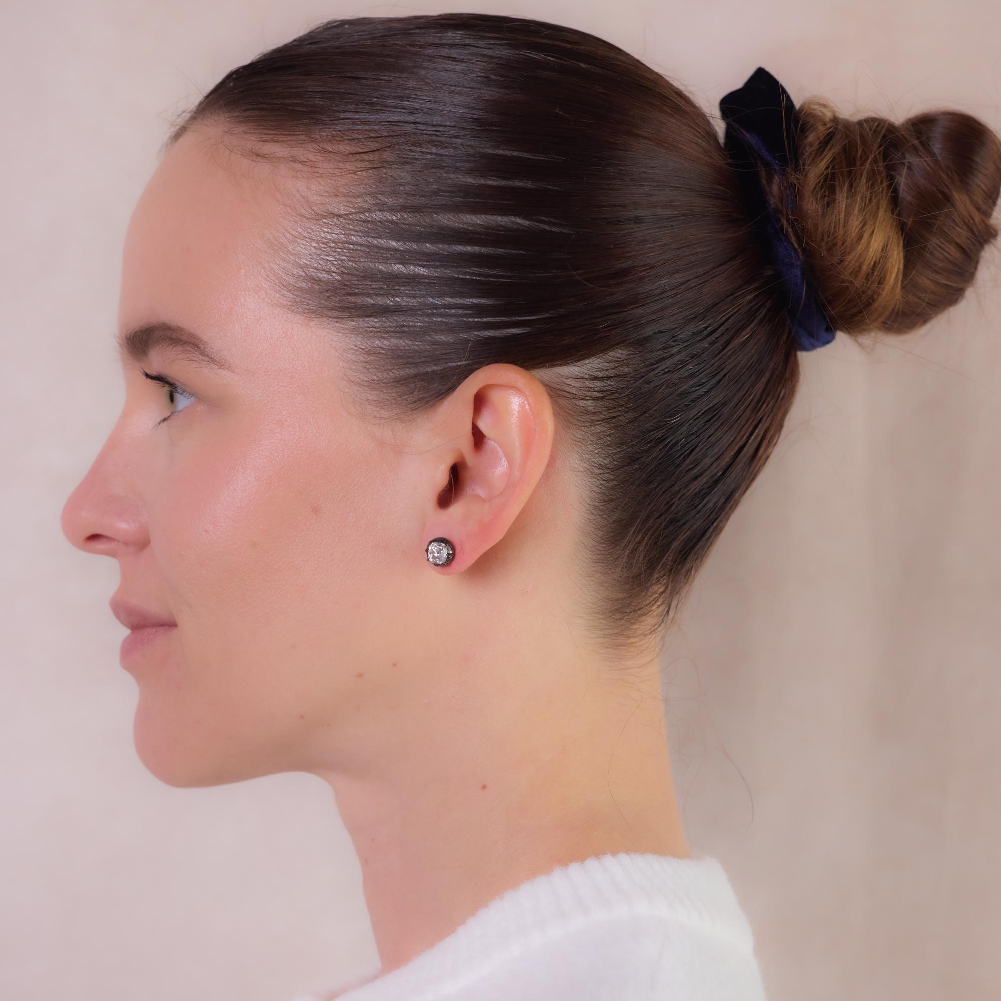 These antique 14k rose gold and silver stud earrings feature two old mine cut diamonds totaling approximately 2.30 carats, H color, I clarity. Originally part of an antique brooch, they retain their original settings, with only posts added for