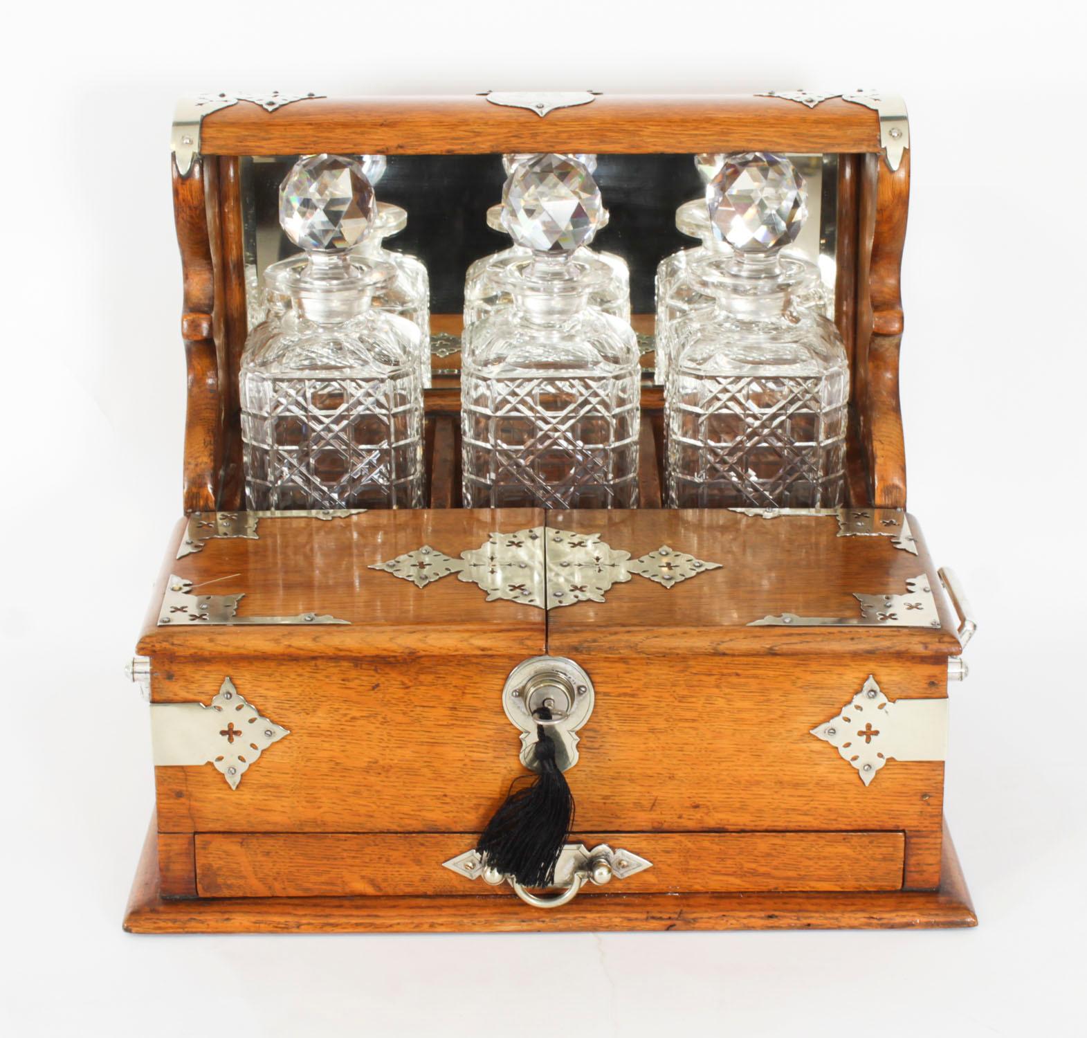 This is a superb antique Victorian golden oak cased three decanter tantalus with decorative silver plated cut brass gothic revival mounts and carry handles to the sides, circa 1880 in date.

This magnificent tantalus features three wonderful hobnail