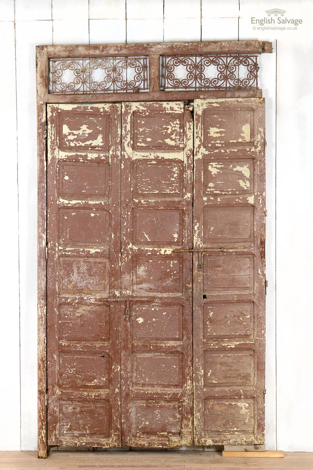 Salvaged antique panel with three multi paneled folding doors and a frame with two ornate metal grille top lights. The size of each folding door is roughly 45cm wide x 212cm high. Wear, chips and dings to doors and frame, rust to grille and the